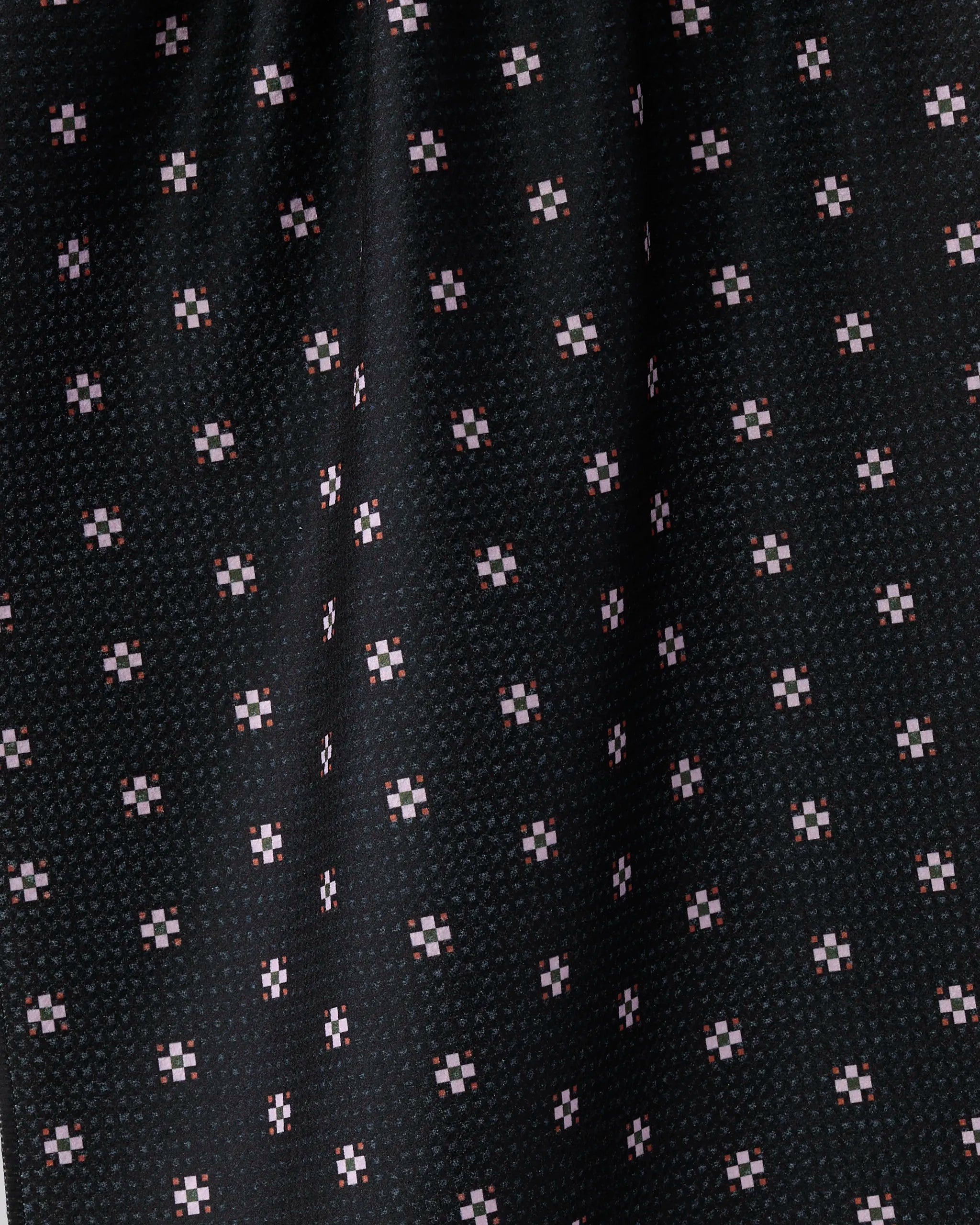 Close-up of Geometry's Night Bloom fabric, crafted from recycled materials. Black surface features a textured grid of small, evenly spaced white and pink square dots with subtle folds.