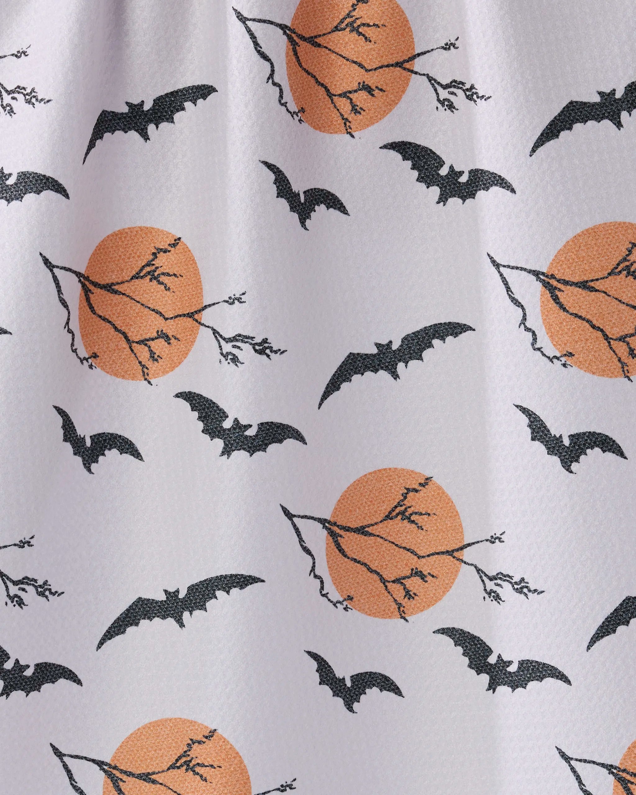 The "Night Flight" tea towel by Geometry features black bats, leafless branches, and orange moons on white recycled fabric.