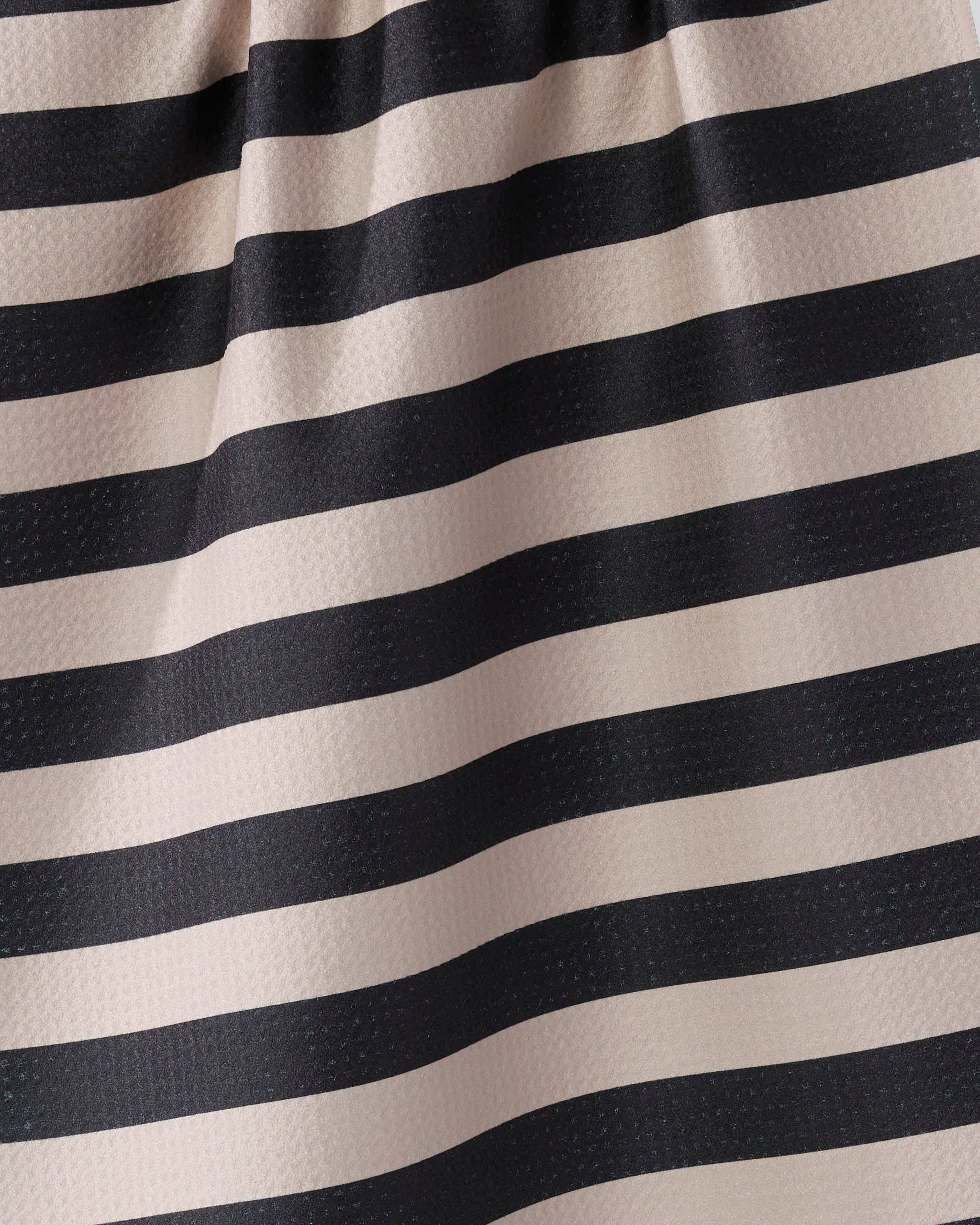 Close-up of Geometry's Night Watch tea towel, featuring horizontal black and beige stripes. Made from ultra-absorbent recycled fabric, the textured material is gathered at the top, creating soft folds and shadows on the pattern.