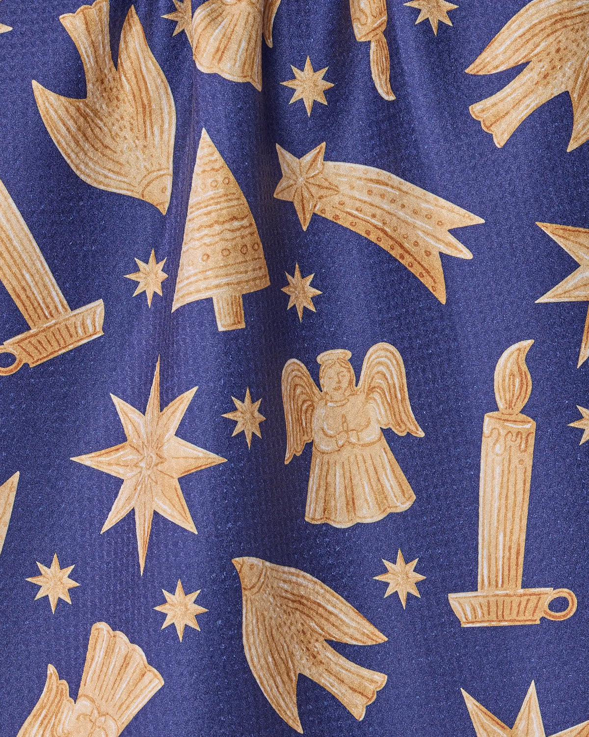 Introducing the Geometry Noel Icons tea towel: a festive and eco-friendly kitchen essential featuring blue fabric adorned with yellow-gold holiday icons such as stars, birds, candles, Christmas trees, an angel, and shooting stars. Crafted from recycled materials and designed with a subtle crinkled texture, this ultra-absorbent towel adds both cheerful style and sustainability to your home.