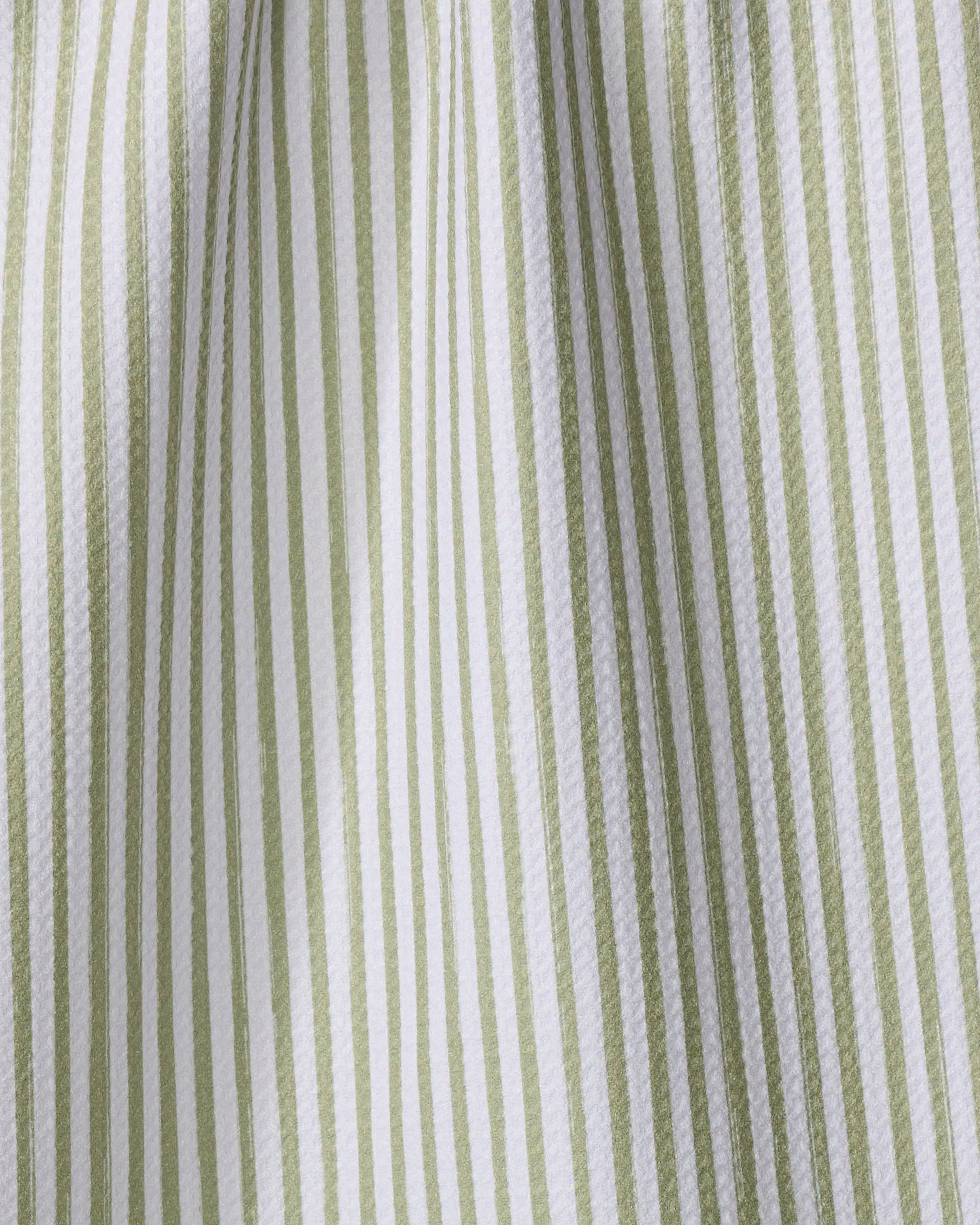 Close-up of the Noel tea towel by Kailee Wright, featuring vertical green and white stripes. Made from recycled materials, its slightly wrinkled texture highlights the eco-friendly fabric’s folds under light and shadow.