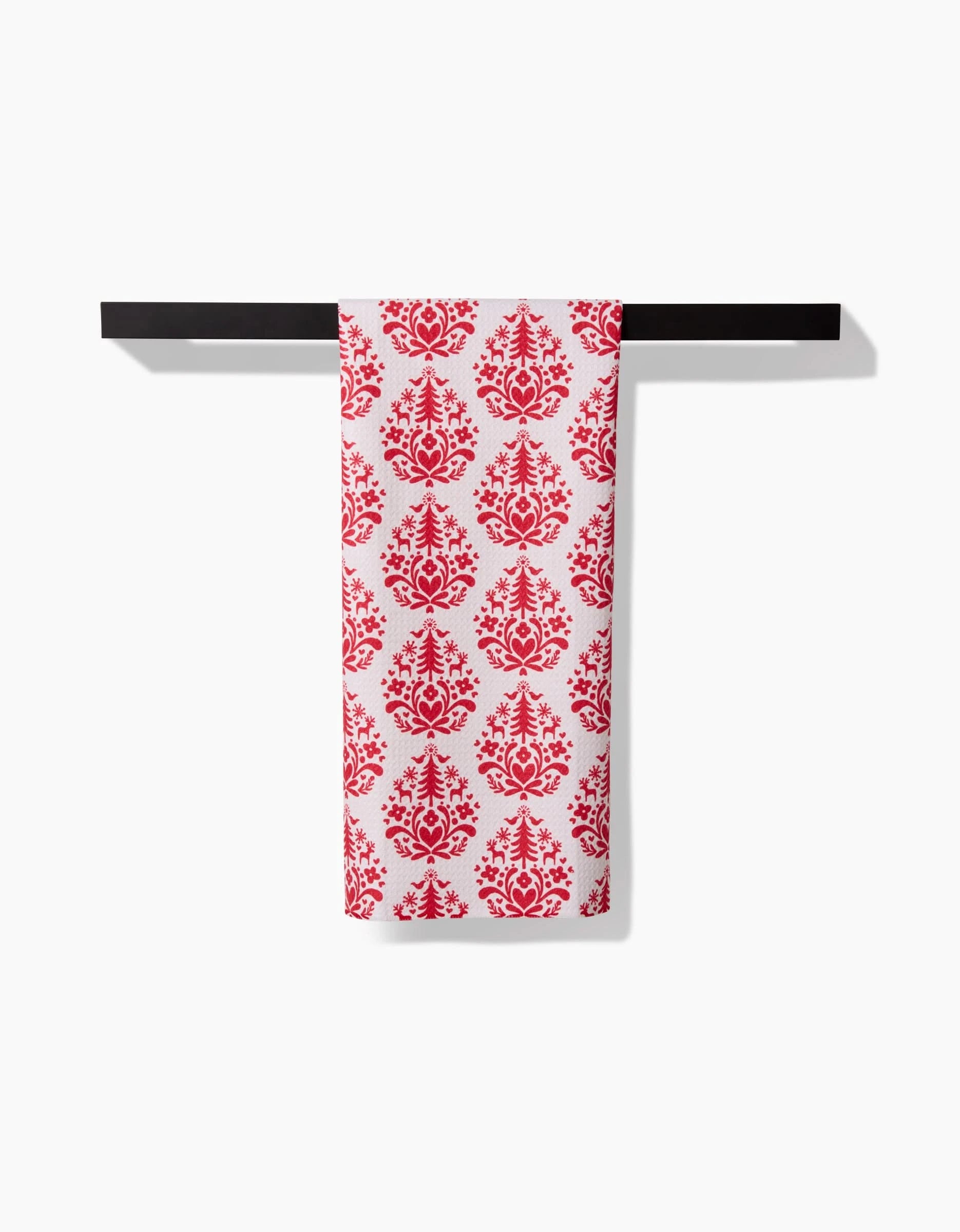 The Kayla Ann Nordic Holiday Stamp tea towel, featuring a red ornate floral pattern and made from ultra-absorbent recycled materials, hangs neatly folded over a black towel bar against a plain white background.