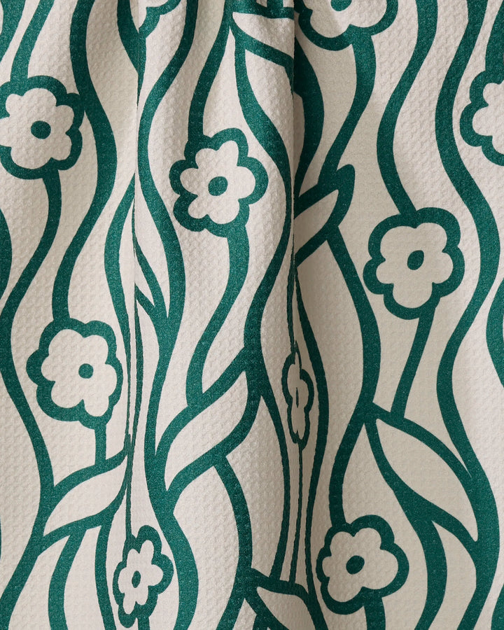 Nostalgic Flowers by Gerdadzy features a green floral and vine design on a textured white tea towel made from recycled materials. Stylized flowers and flowing lines give this quick-drying fabric an organic, decorative look.