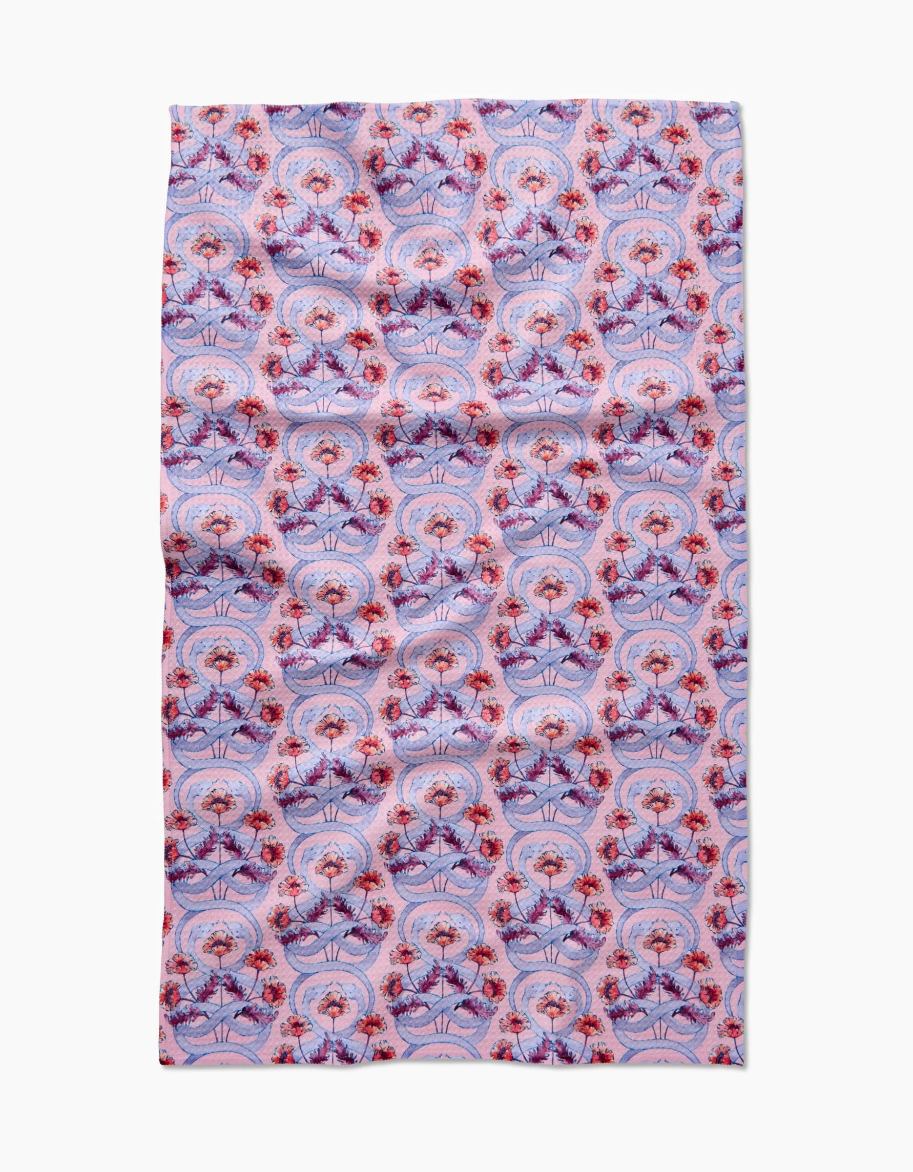 The Nouveau Snake by Maayan Alper-Swan is a rectangular Geoweave fabric featuring a symmetrical, intricate design of red and purple flowers with decorative shapes on a light pink background. Ultra-absorbent and laid flat.