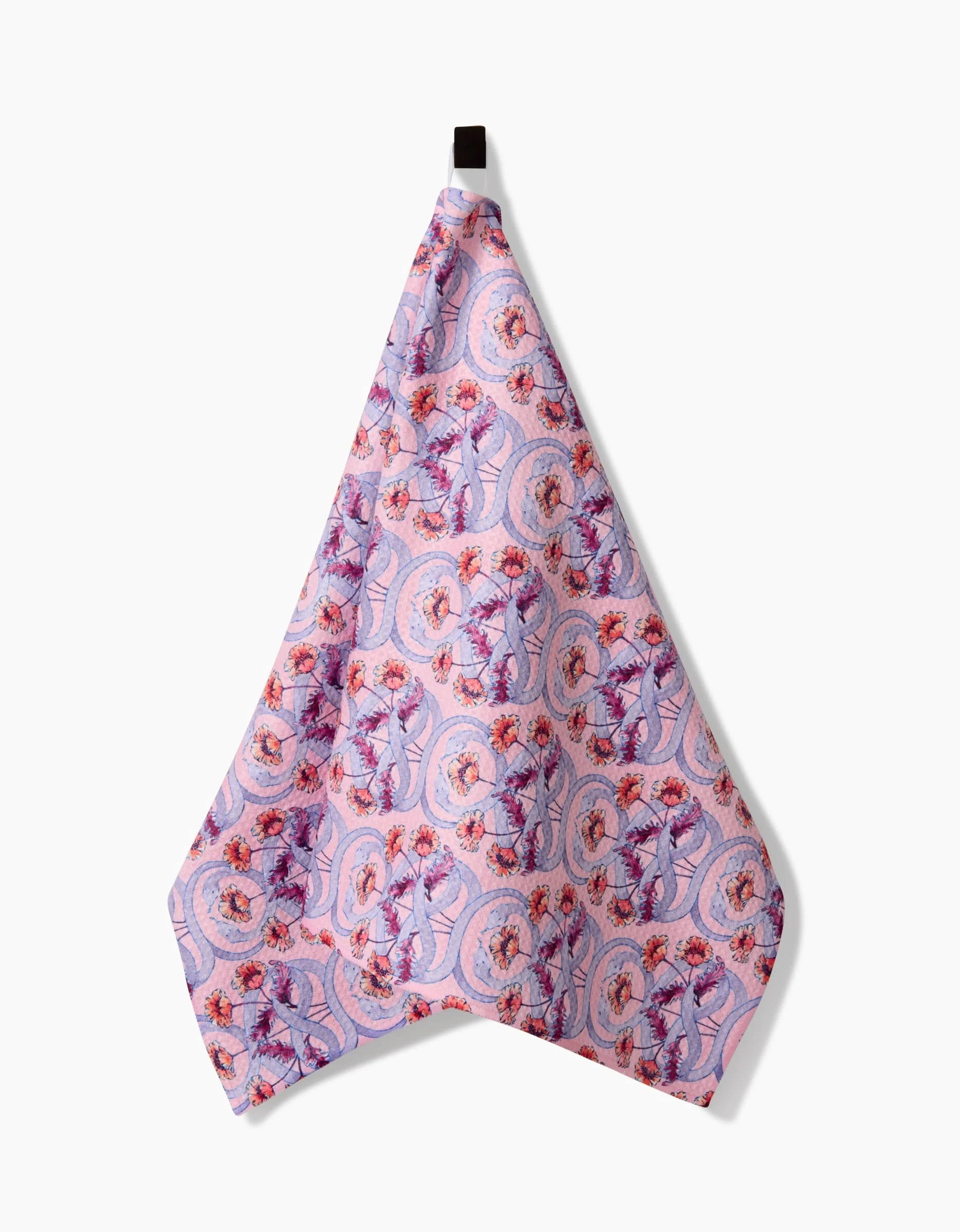 The Maayan Alper-Swan Nouveau Snake towel, in pink and purple with a detailed floral and circular pattern, is made from ultra-absorbent Geoweave fabric and hangs from a black loop against a white background.