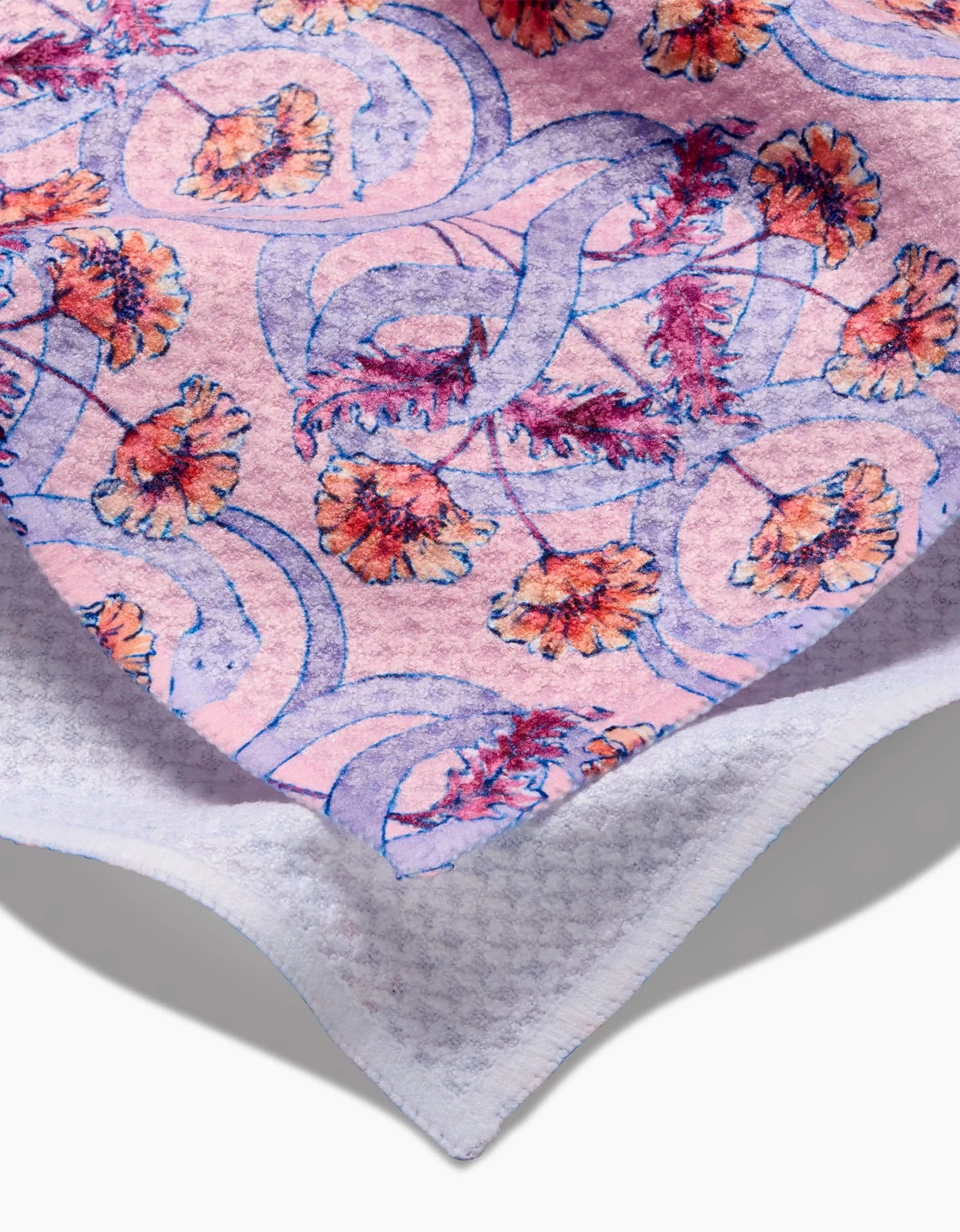 A close-up of the Nouveau Snake by Maayan Alper-Swan—a soft, ultra-absorbent fabric with a vibrant purple serpent and orange flower pattern on pink, finished with a white, waffle-textured edge.