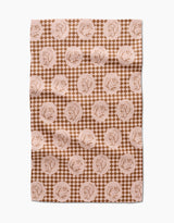 The “Nuts About You” tea towel by Aubrey Fairchild features a brown and beige circular squirrel design over small diamonds. Made of quick-drying fabric, it appears slightly wrinkled and is displayed on a white surface.