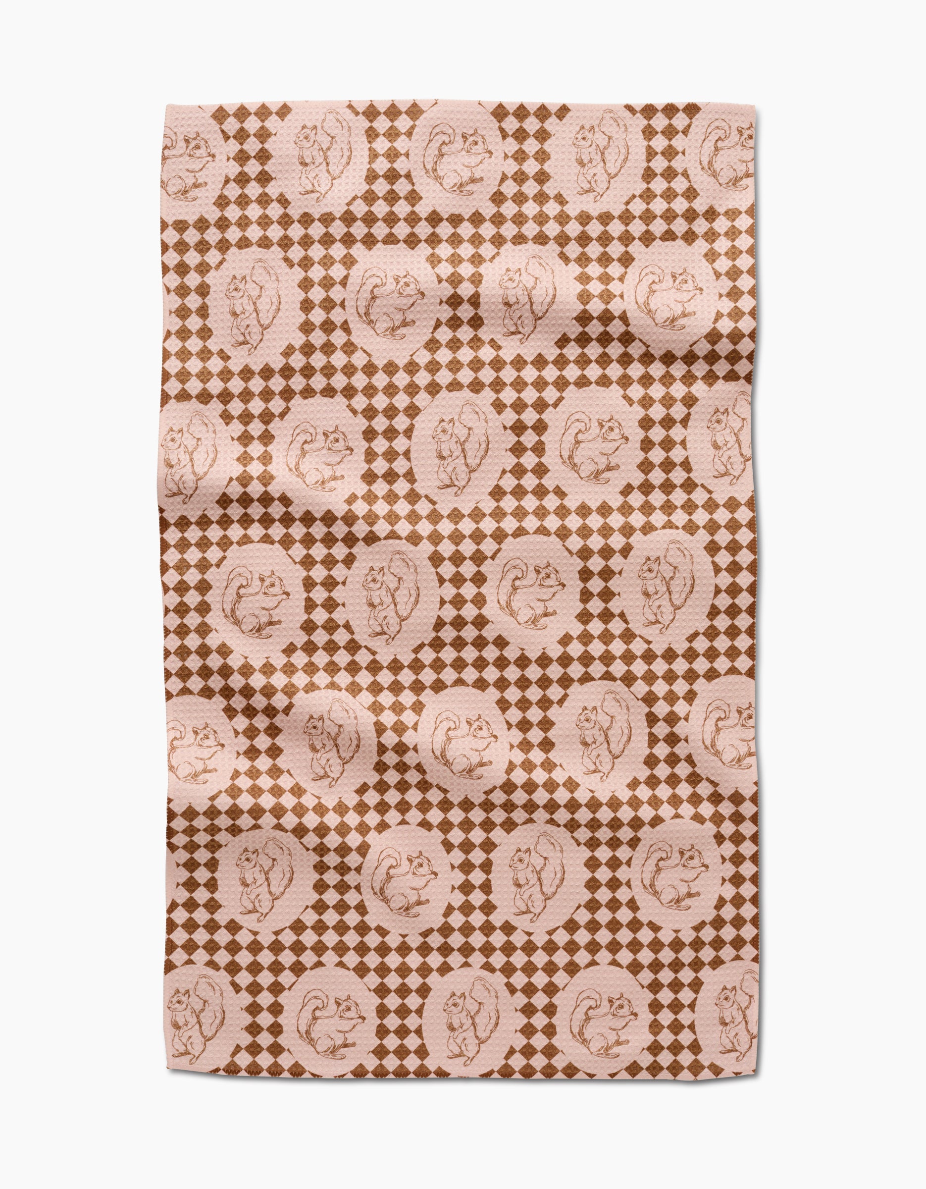 The “Nuts About You” tea towel by Aubrey Fairchild features a brown and beige circular squirrel design over small diamonds. Made of quick-drying fabric, it appears slightly wrinkled and is displayed on a white surface.