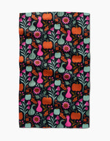 The Oakley kitchen towel by Amy MacCready features a vibrant folk art design of pumpkins, gourds, flowers, and leaves in orange, pink, teal, and green on a black background for a whimsical touch.
