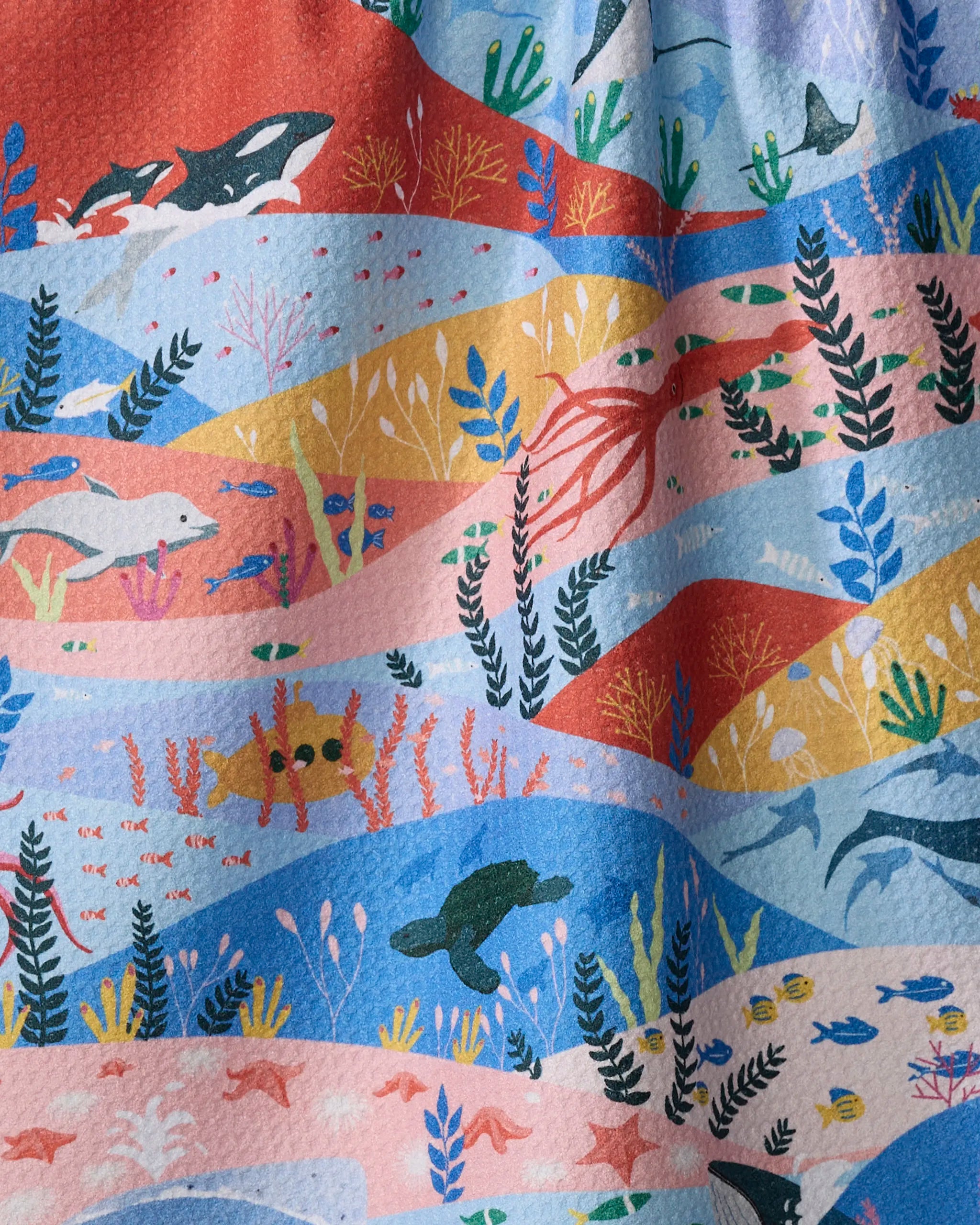 The "Oceans" tea towel by Ceyda Alasar features vibrant underwater designs with whales, dolphins, an octopus, and coral on colorful backgrounds—an ultra-absorbent towel perfect for brightening any kitchen.