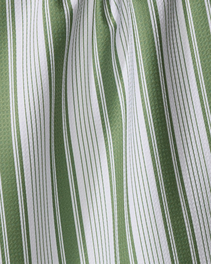 A close-up of Aubrey Fairchild’s “Of the Same Stripe” tea towel, made from recycled materials, shows vertical green and white stripes in varying thicknesses with soft folds and shadows accentuating its textured fabric.