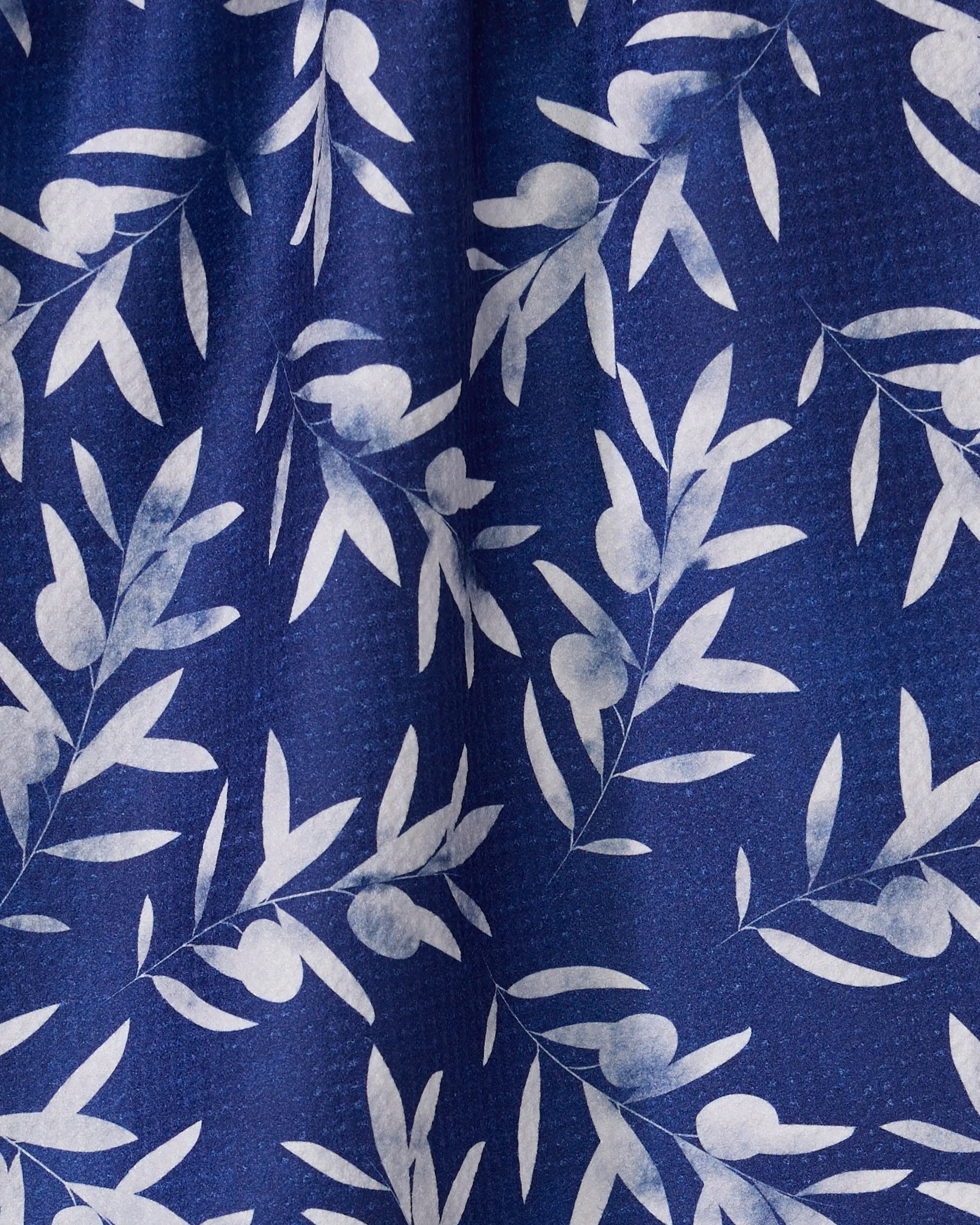 The Olive Branch kitchen towel by Geometry features white leafy and berry-like patterns on textured dark blue fabric, showcasing repeating botanical branches. Made from recycled materials, it adds natural charm to your kitchen.