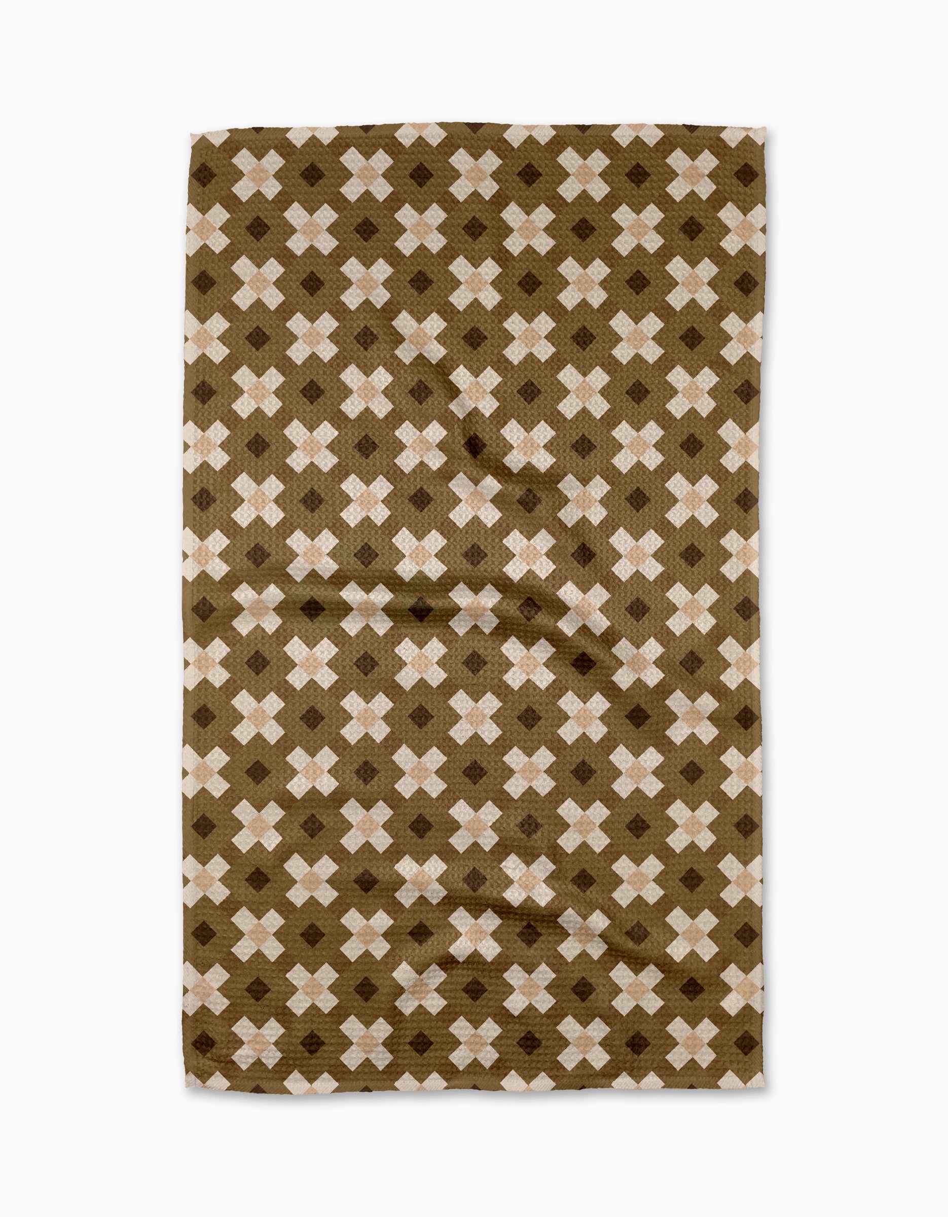 The Olive Geo tea towel by Teri the Butter features a quick-drying rectangular fabric with a light brown background and repeating white and dark brown X-shaped geometric patterns. The texture has a slightly wrinkled appearance.