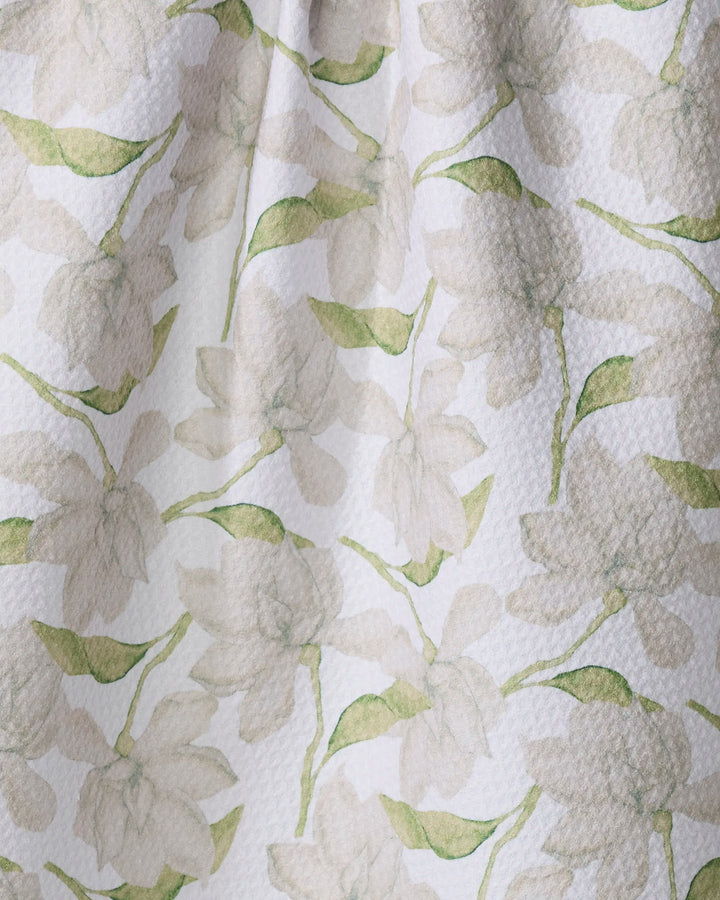 A close-up of Aubrey Fairchild's Once and a Floral shows textured fabric with light, watercolor-style white flowers and green leaves on white—ideal for a quick-drying tea towel.