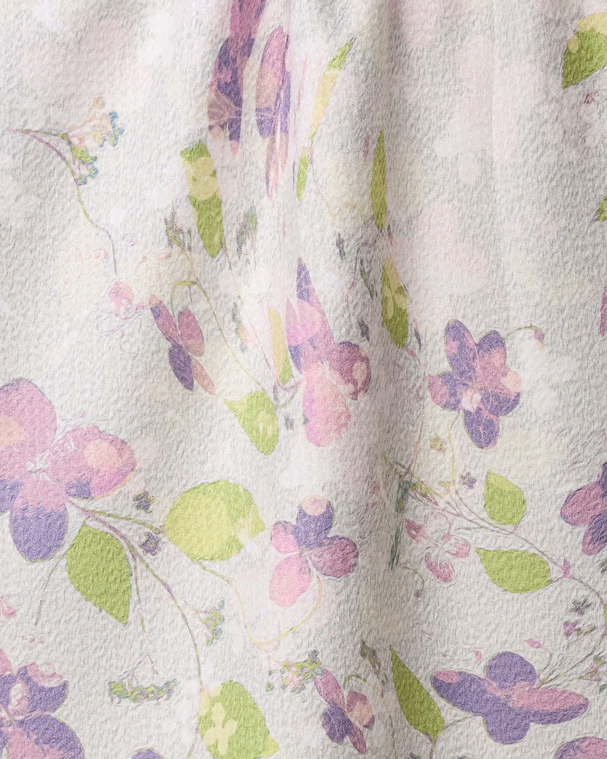The Geometry Ophelia Garden tea towel features a pastel floral pattern in pink, purple, and green on a light background. Made from recycled materials, it adds a soft, spring-like touch to any kitchen.