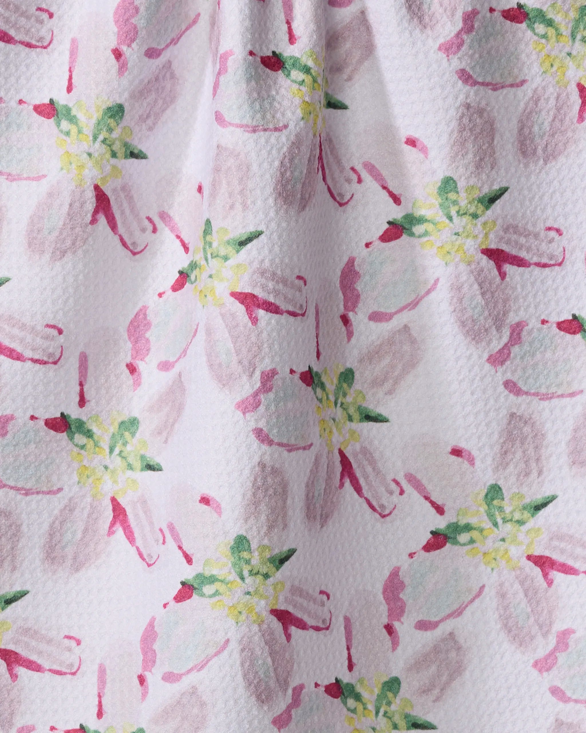 A close-up of the Orchard in Bloom tea towel by Ania Zwara Art shows its pink, green, and yellow watercolor floral design on textured white fabric. Loosely painted flowers provide a soft look, while the ultra-absorbent material offers practical beauty.