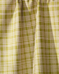 A detailed view of Geometry’s Orchard Plaid Green curtain features a yellow-green grid reminiscent of a tea towel. The eco-friendly fabric is gathered at the top, forming soft vertical folds.
