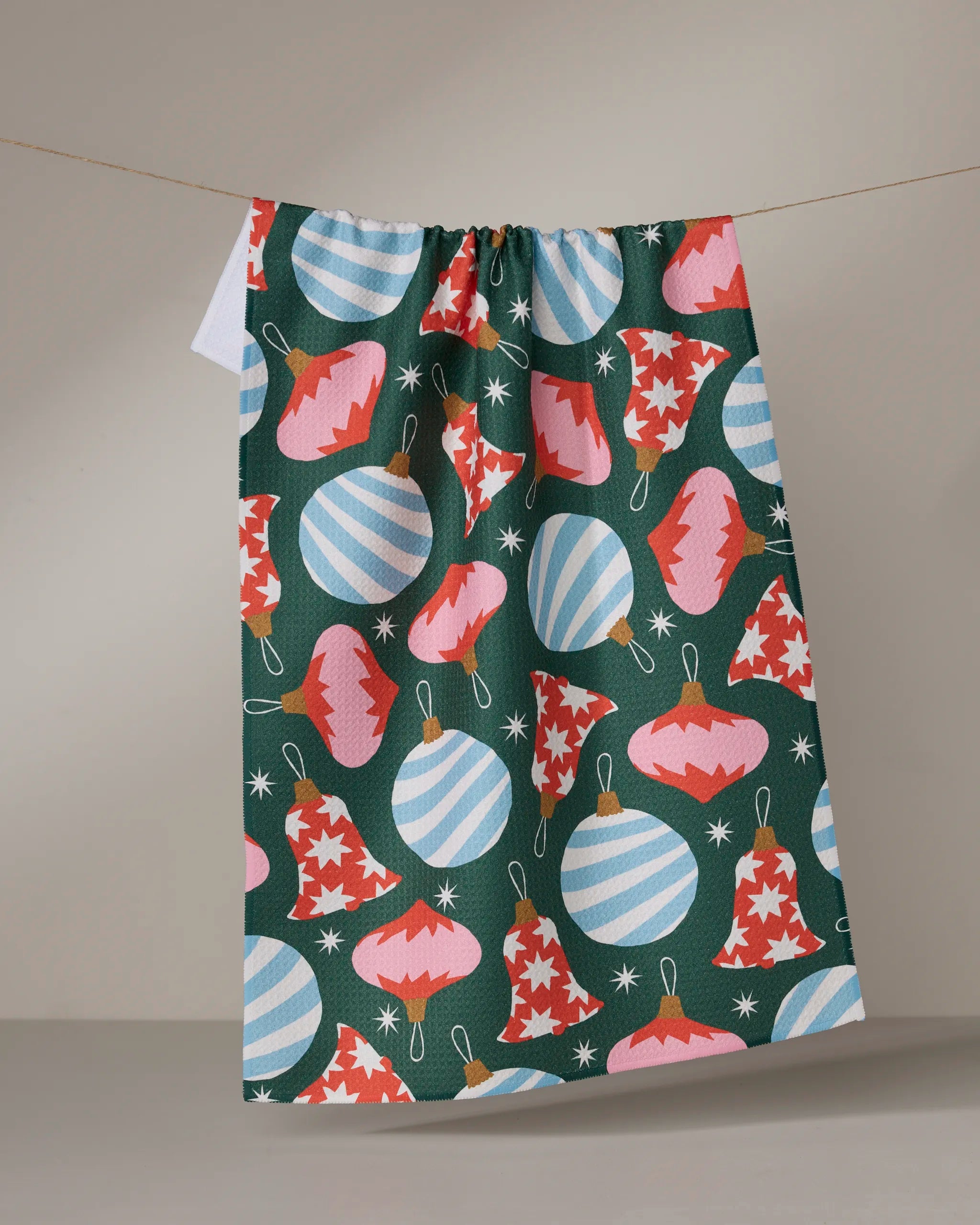 The Geometry Ornamenta dish towel features blue striped round ornaments and red star-patterned and zigzag bell ornaments on a dark green background, adding a festive touch to your kitchen decor.