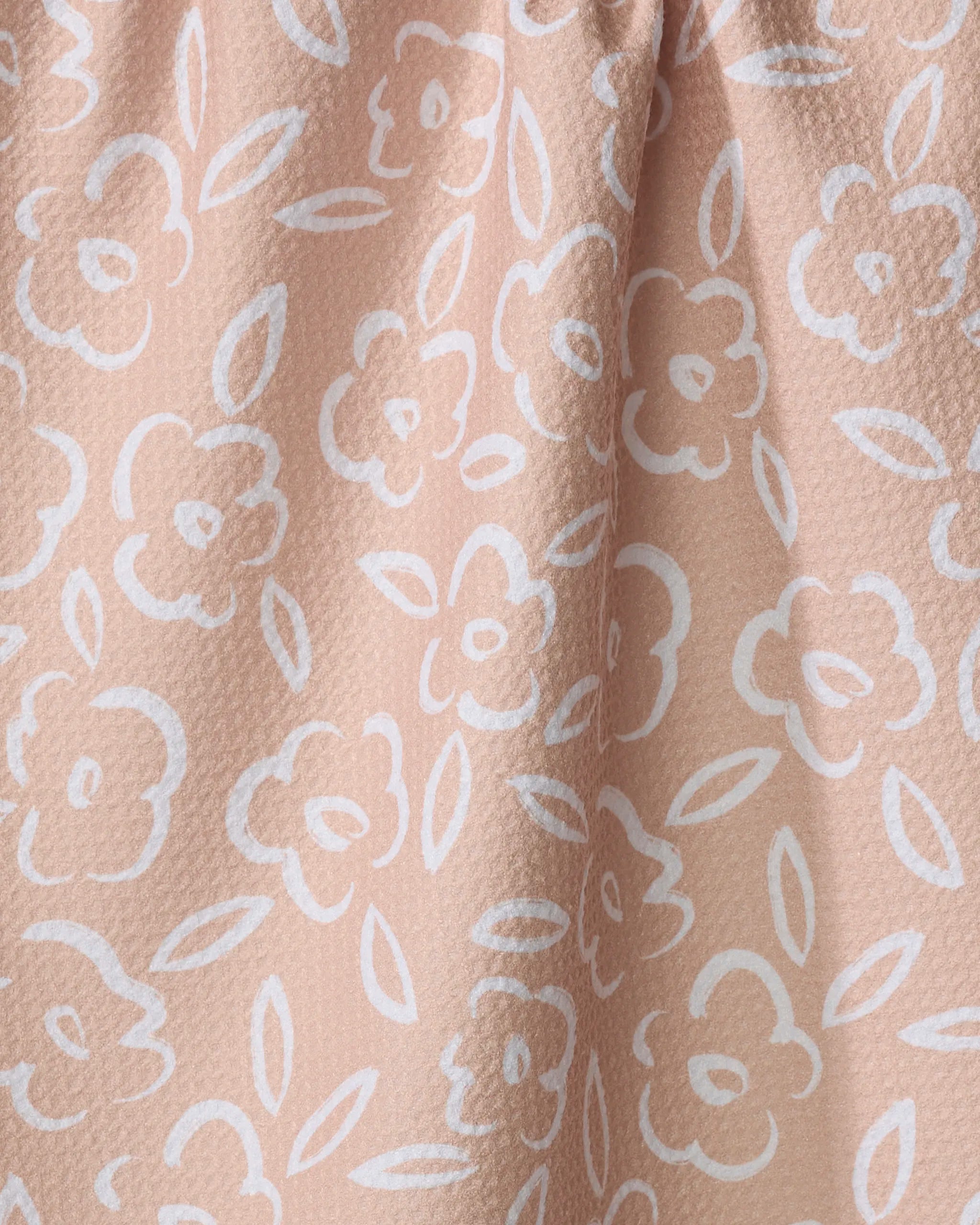 Close-up of Painted Bloom by Hufton Studio—light pink textured fabric with a white floral pattern, featuring simple flowers and leaves. Perfect as an absorbent dish towel or recycled kitchen towel for daily use.
