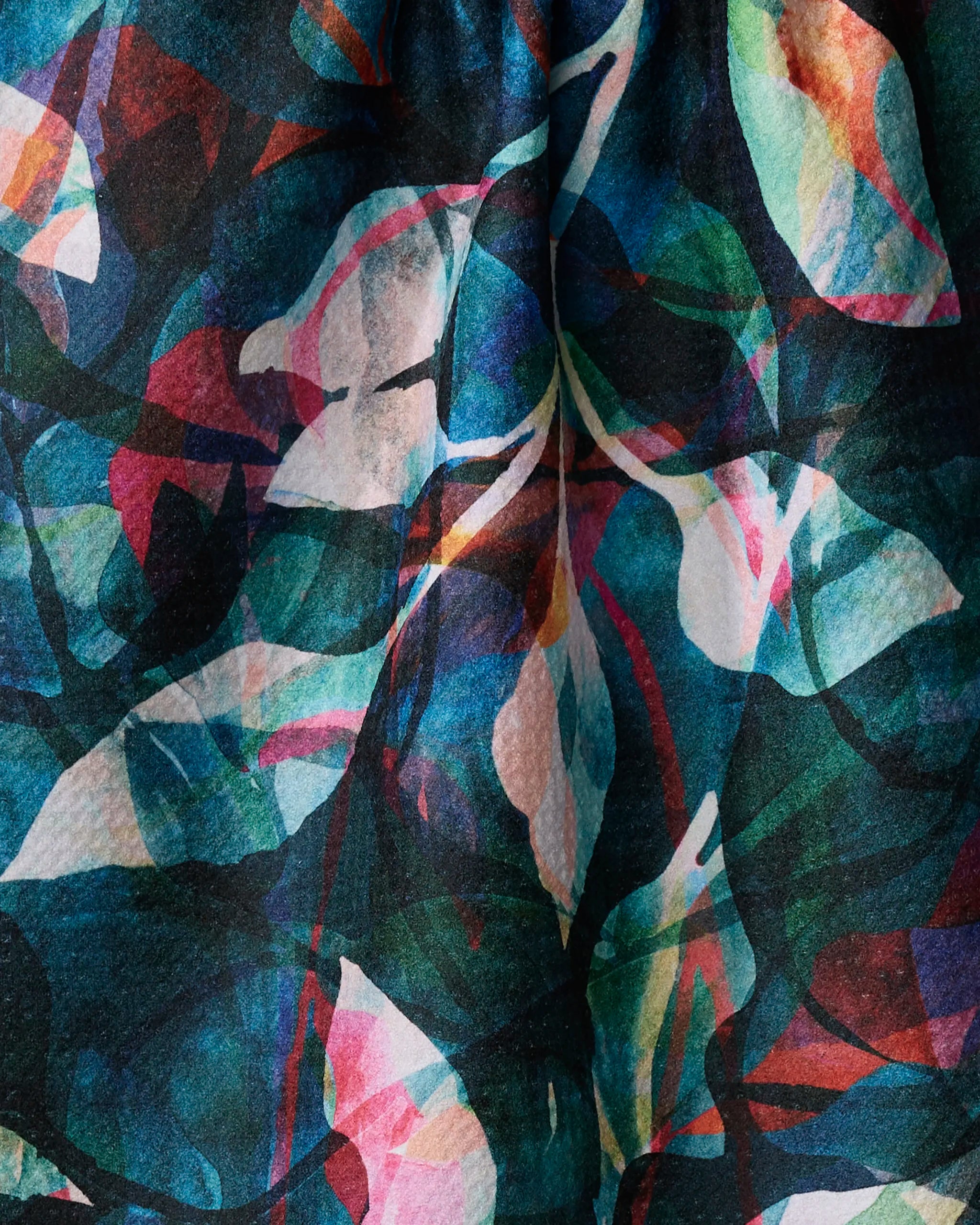 The "Painted Foliage Teal" kitchen towel by Rachel Parker features an abstract pattern of overlapping green, blue, pink, and white leaves, creating a vibrant design that adds both style and function to your space. Ultra-absorbent for everyday use.