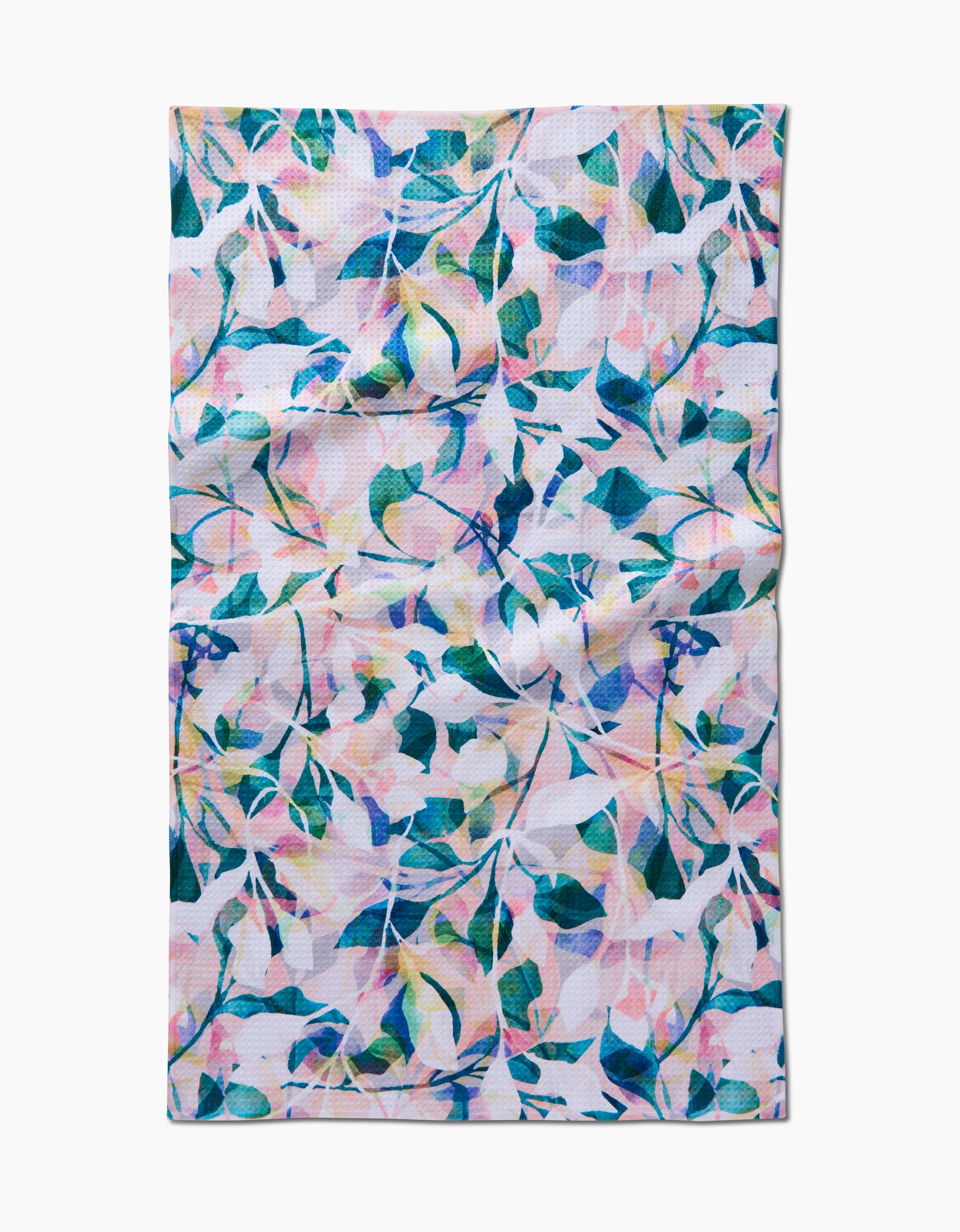 Painted Foliage by Rachel Parker: a rectangular tea towel with a vibrant abstract leaf and branch pattern in blue, green, pink, and yellow on white. Made from Geoweave fabric using recycled materials; slight natural wrinkling appears in the fabric.