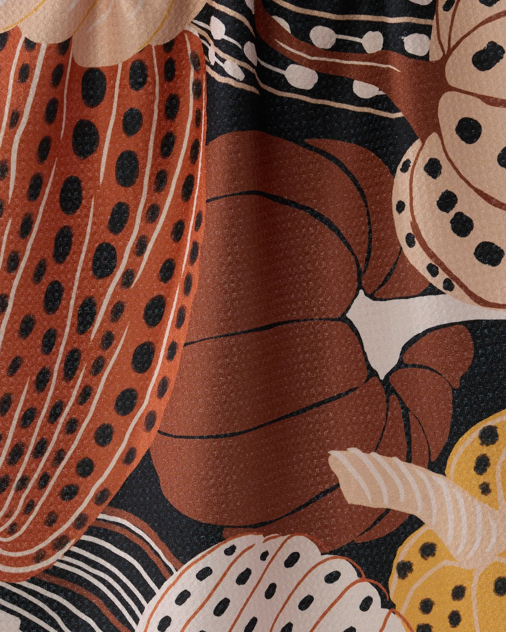 Close-up of Geometry's Painted Patch kitchen towel, adorned with abstract, overlapping pumpkins and gourds in orange, cream, yellow, and black with dotted and striped accents. Made from recycled materials.