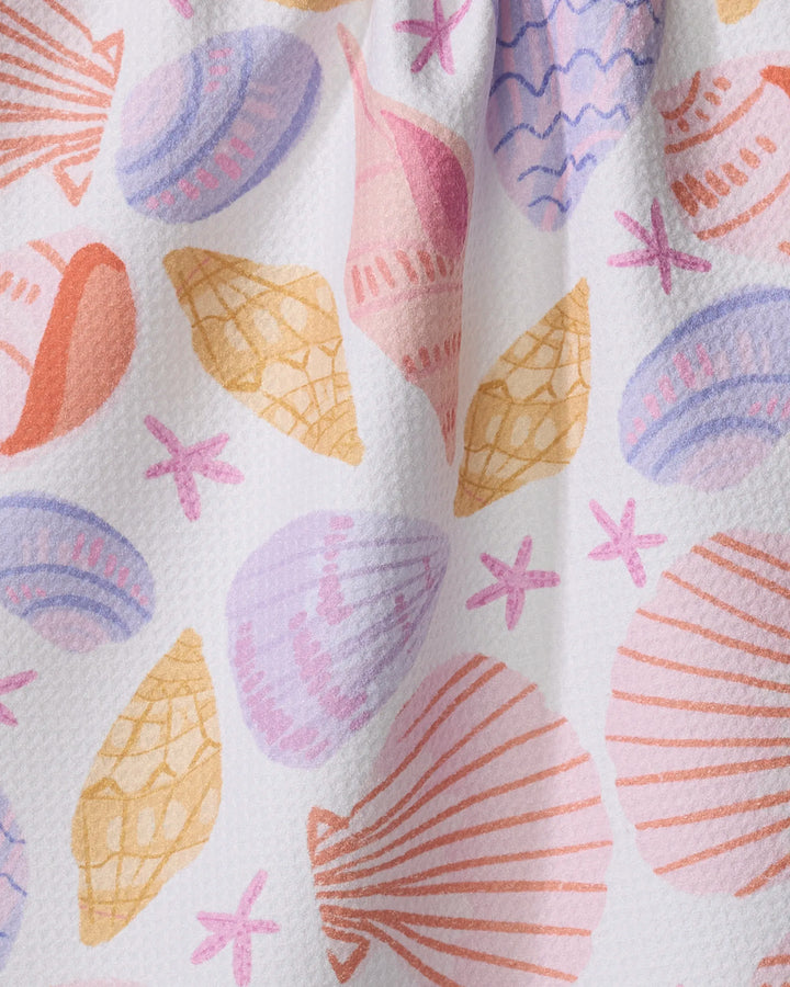 The Painted Shells tea towel by Janna Sue Design features a hand-drawn look with pink, orange, and purple seashells and starfish on white, made from recycled materials.