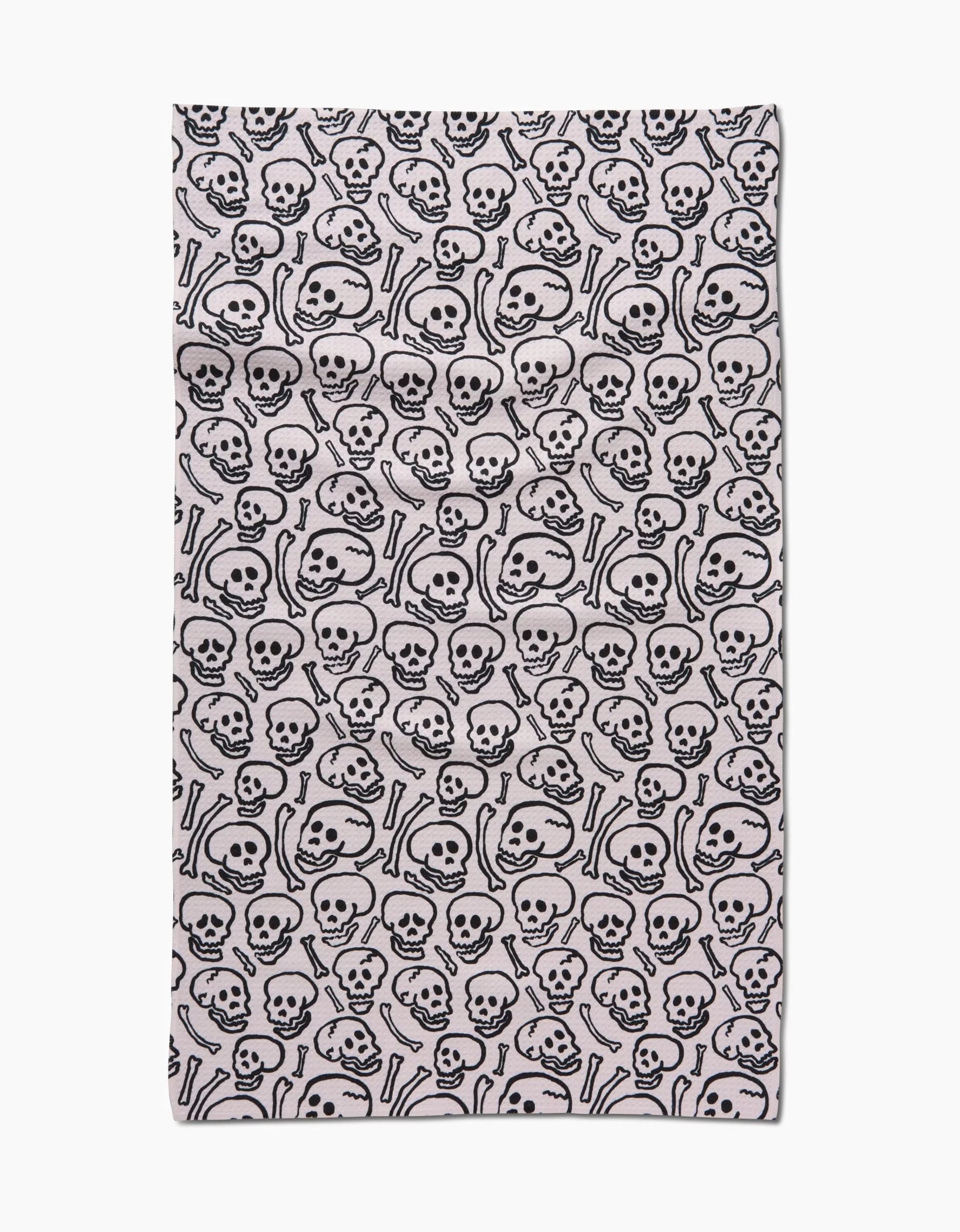 The Painterly Skulls tea towel by Kayla Ann features a bold black and white cartoon skulls and bones pattern on ultra-absorbent Geoweave™ fabric, with striking black outlines densely covering the crisp white surface.