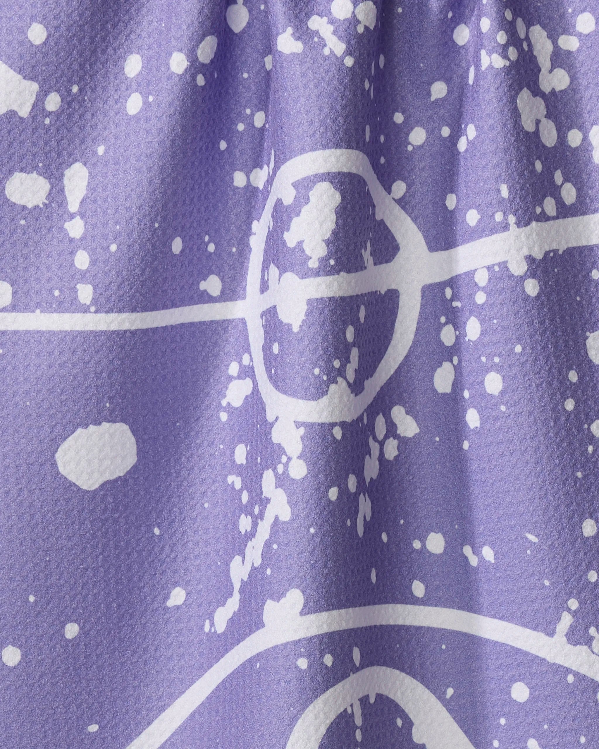 The Sissy Moon "Parquet" kitchen towel features purple fabric with white abstract splatter and line patterns, a slightly textured surface, and visible folds that create dynamic shadows—ultra-absorbent and stylish for any kitchen.