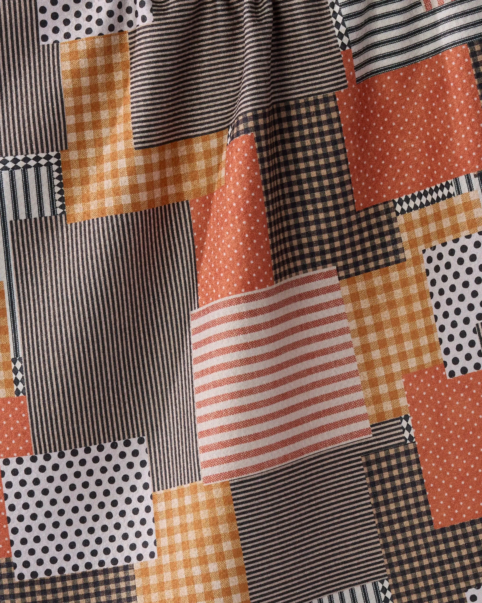 A close-up of Geometry’s Patch and Pumpkin shows recycled patchwork fabric with black, white, and orange squares in stripes, polka dots, checks, and gingham patterns.