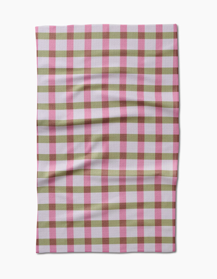 The Patricia Plaid by Laura Prietto is a rectangular tea towel featuring a pink, red, and white gingham checkered pattern, shown flat with visible creases.