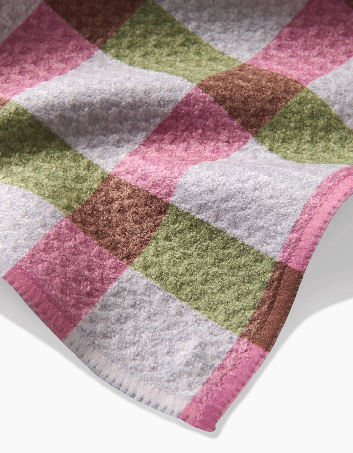 The Patricia Plaid by Laura Prietto is a soft, textured tea towel featuring pink, green, brown, and white checks. Made from recycled materials and finished with neat edges for a stylish touch.