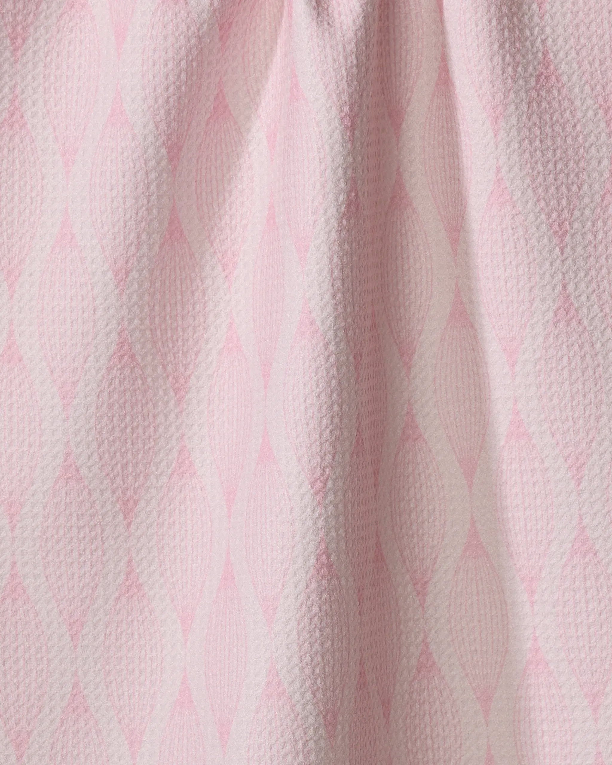 Close-up of Shelley Smith’s “Patterned in Pink” kitchen towel, featuring a repeating diamond pattern in soft pink and white. Made from recycled materials, the fabric is slightly gathered at the top for gentle folds.