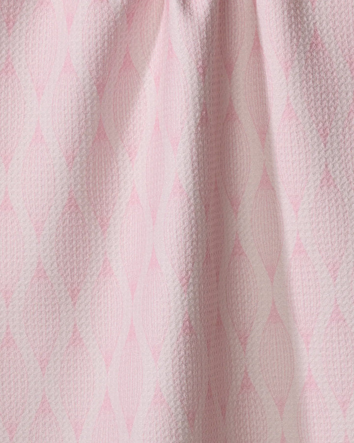Close-up of Shelley Smith’s “Patterned in Pink” kitchen towel, featuring a repeating diamond pattern in soft pink and white. Made from recycled materials, the fabric is slightly gathered at the top for gentle folds.