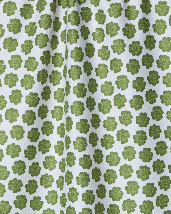 The Geometry Patty is a white recycled kitchen towel featuring a repeating green four-leaf clover pattern. Its fabric displays subtle folds and shadows for a textured look.