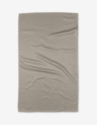 The Jenny Keller Pebble towel, a rectangular beige ultra-absorbent piece with small black polka dots, is laid flat to reveal gentle wrinkles and soft folds against a white background.