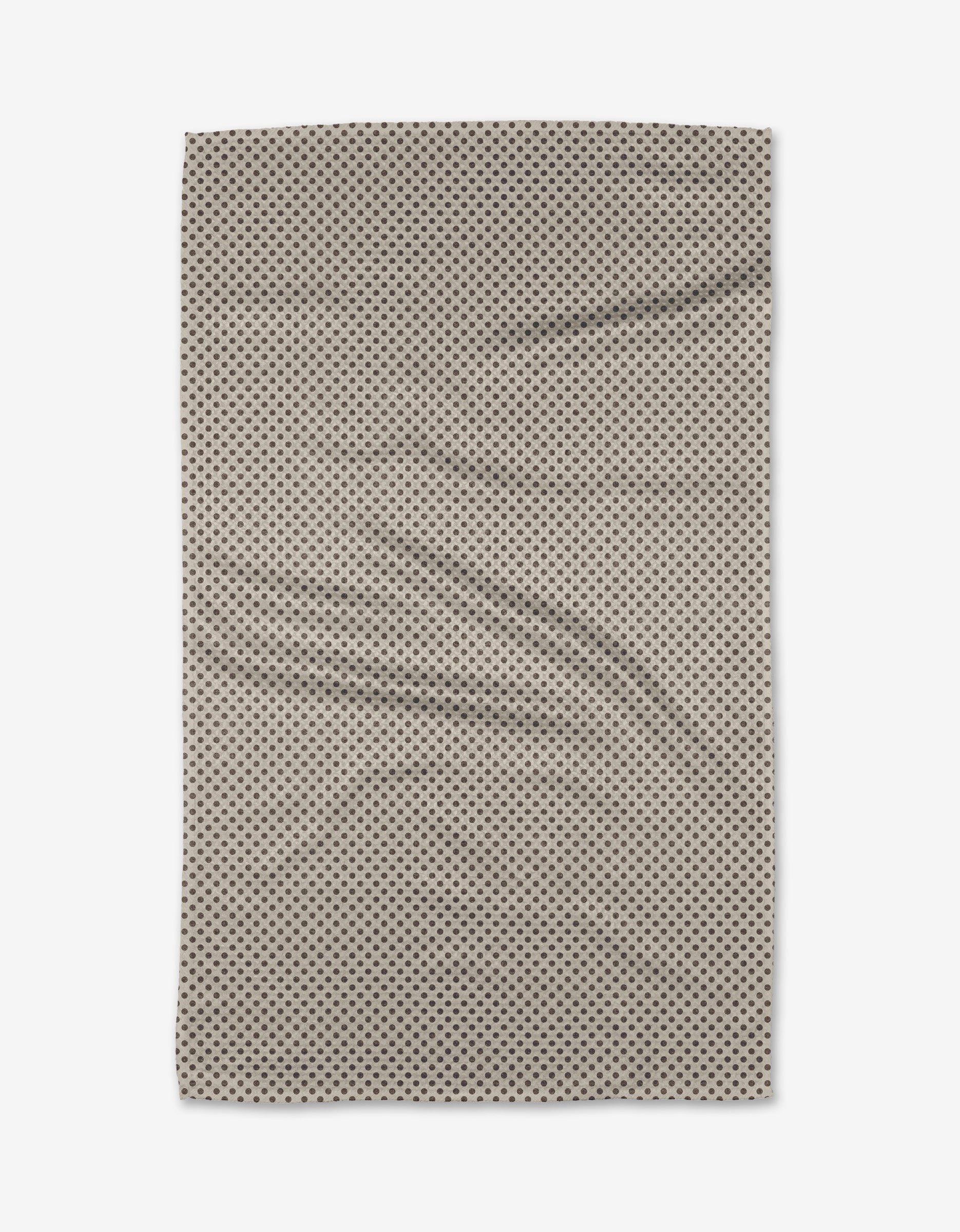 The Jenny Keller Pebble towel, a rectangular beige ultra-absorbent piece with small black polka dots, is laid flat to reveal gentle wrinkles and soft folds against a white background.
