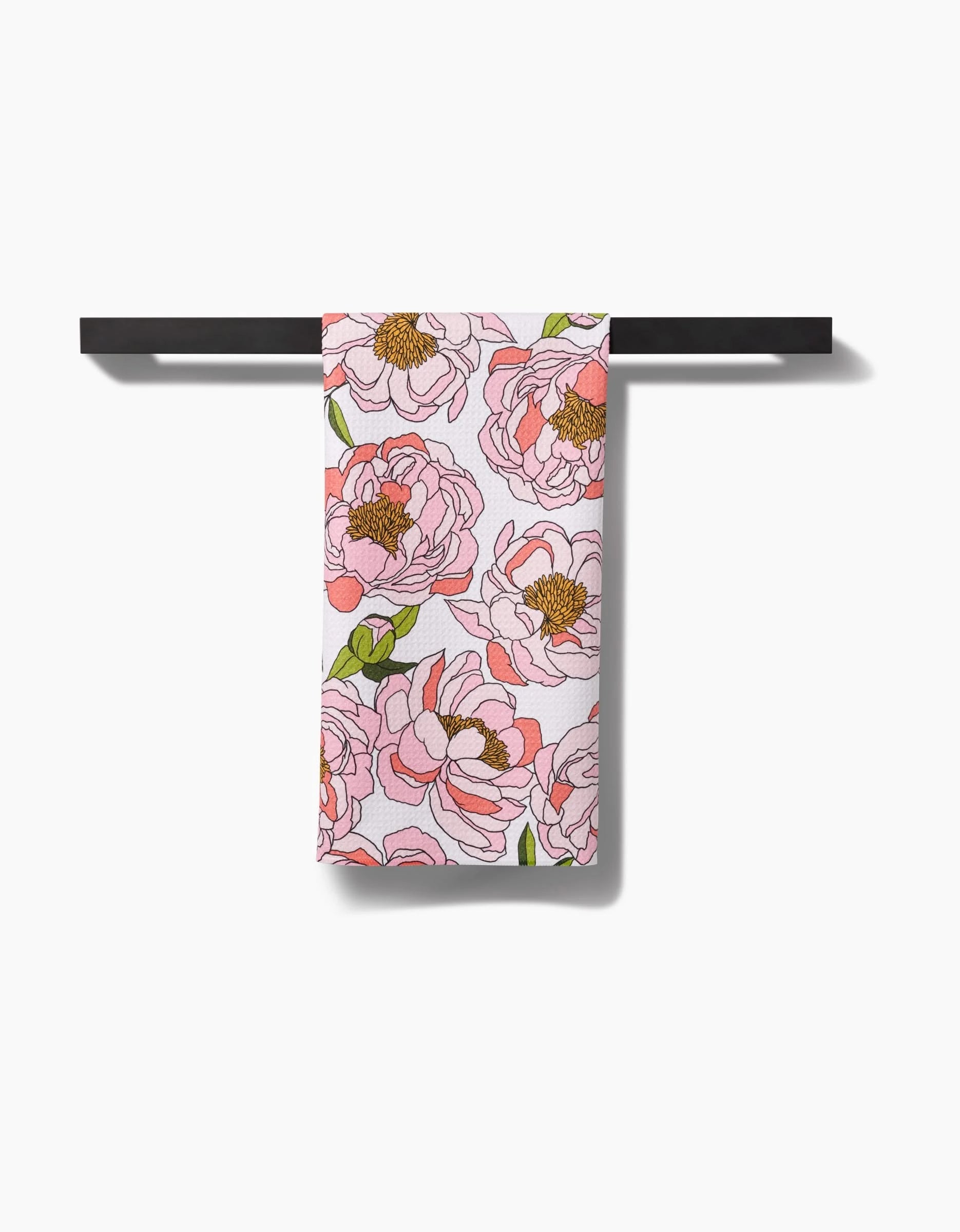The Peony Paradise towel, made from ultra-absorbent Geoweave fabric with a pink floral peony and green leaf design, hangs neatly on a black bar against a white background.
