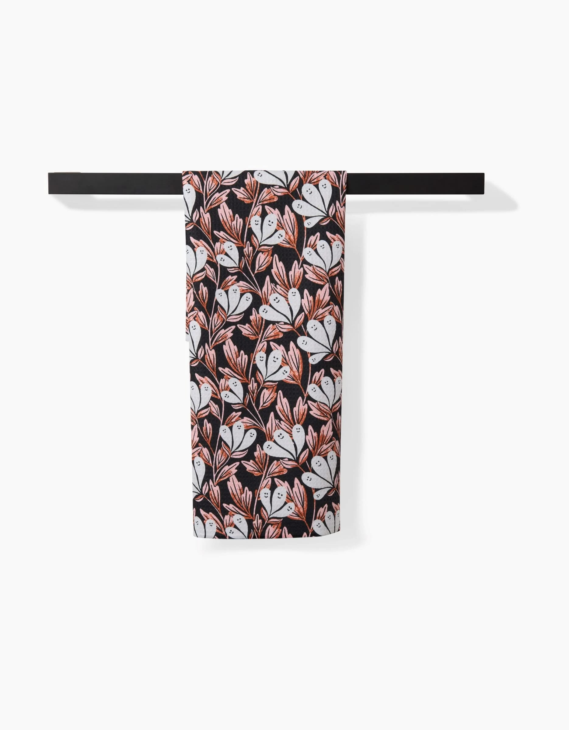 The Sarah Daugherty Phantom Floral towel, ultra-absorbent with a black base and white-orange floral design, is neatly folded over a horizontal black bar against a white background.