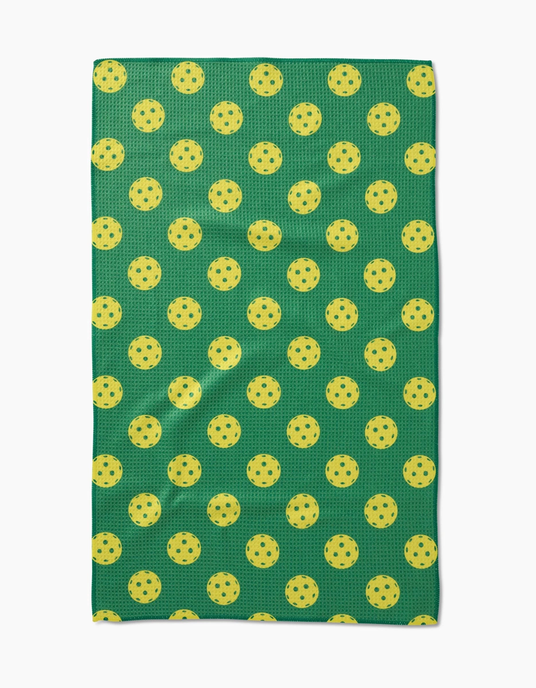 The GEOMETRY Pickleball tea towel is green, rectangular, made of Geoweave fabric, and features a pattern of evenly spaced yellow pickleballs.