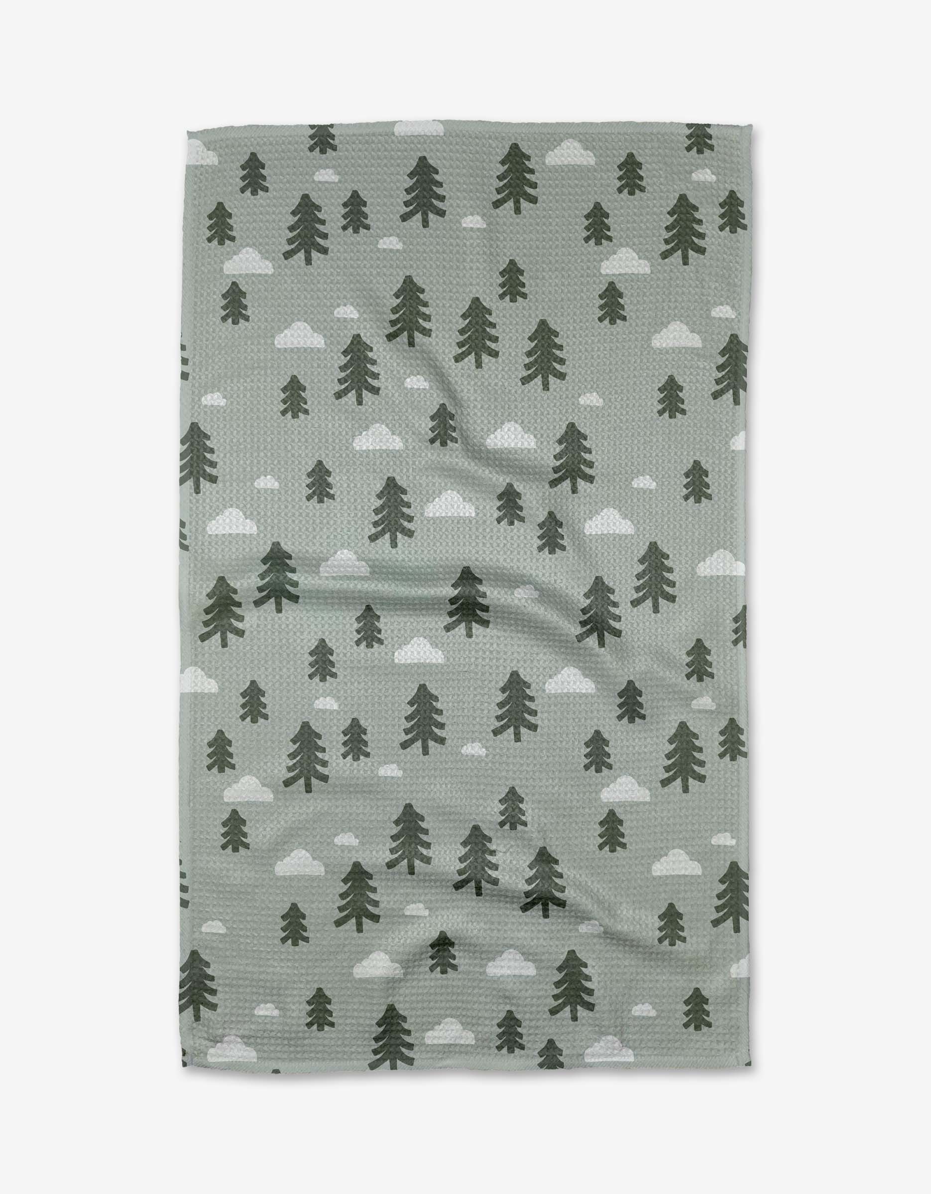 The Pine Forest Tea Towel by Coit Creative is a green, rectangular towel made from Geoweave™ fabric, featuring dark green pine trees and white clouds patterned across the surface.