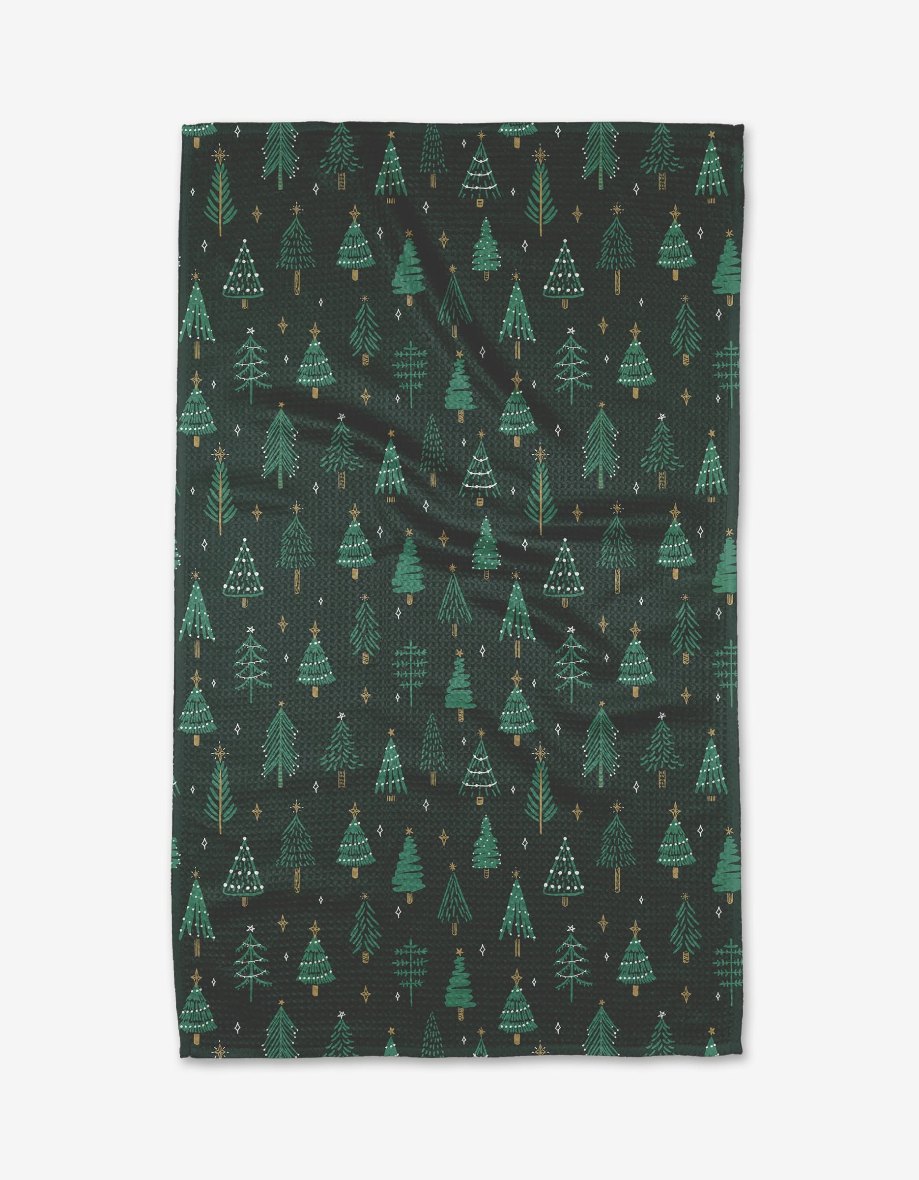 The Pine X-mas tea towel by Hufton Studio features a dark background with green Christmas trees and yellow stars in a repeating pattern. Made from recycled materials, the slightly wrinkled fabric is shown on a white backdrop.