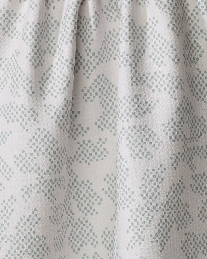 Close-up of the Pixie Sage dish towel by Studio Jeannot in light grey, showcasing a quick-drying fabric with a soft feel. The subtle dotted pattern forms an abstract floral or leaf design, adding gentle texture and charm.