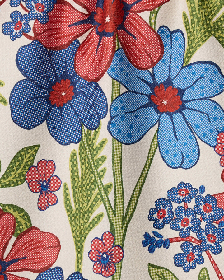 The Plaid Floral tea towel by Geometry features a vibrant red and blue floral pattern with green stems on a textured white background. Vintage dots add charm, while recycled materials make it an eco-friendly choice.