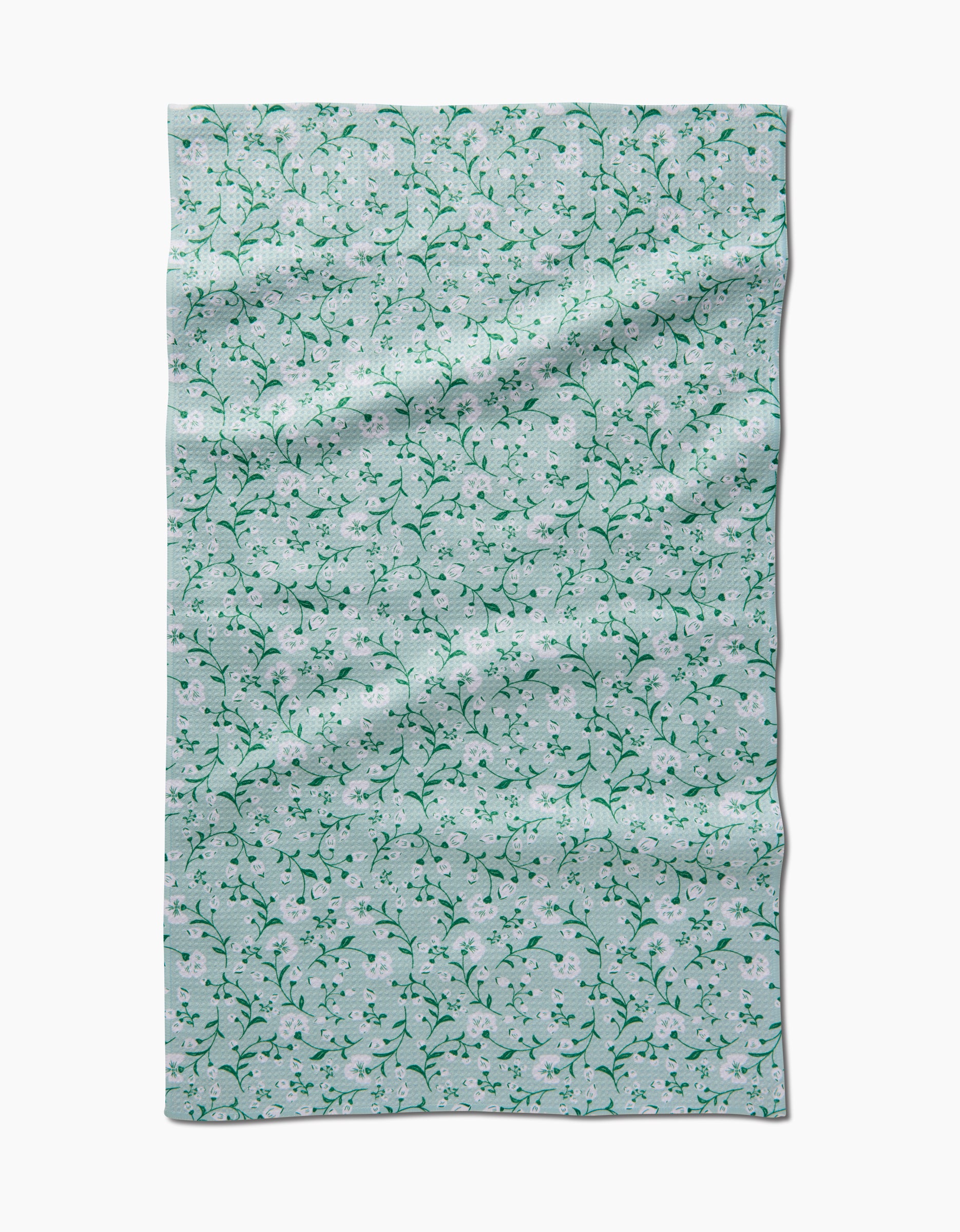 Plumbago Bloom by Danelys Sidron features a light blue Geoweave fabric with a pattern of small white flowers and green vines, shown flat with visible creases and folds.