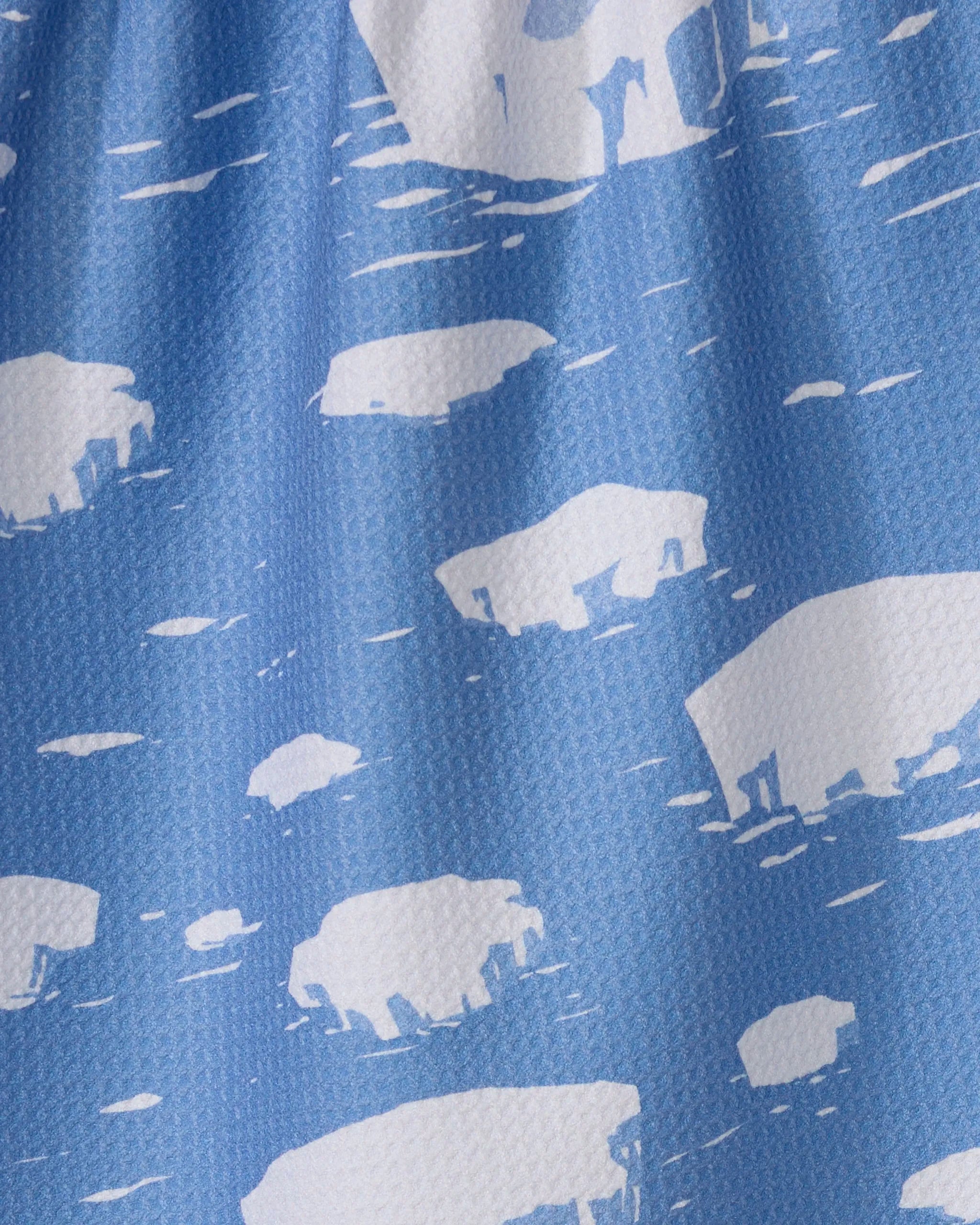 Close-up of Geometry's Polar Float tea towel in blue, featuring ultra-absorbent fabric and a white polar bear with ice floe pattern against a textured backdrop.