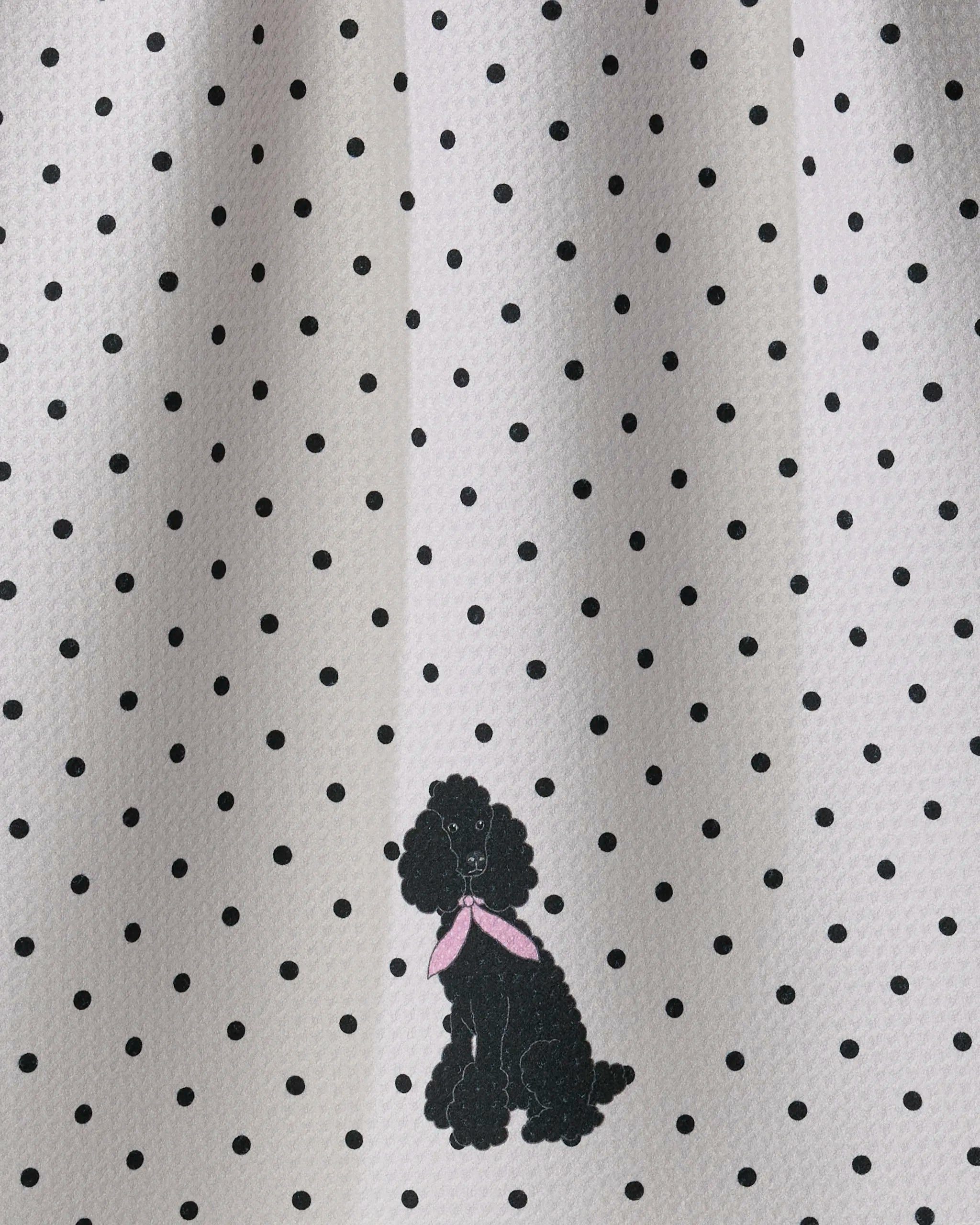 The “Poodle Charm” towel by Geometry features a white fabric with evenly spaced black polka dots and a small black poodle sporting a pink scarf near the bottom center, offering ultra-absorbency while adding a charming accent to your kitchen décor.