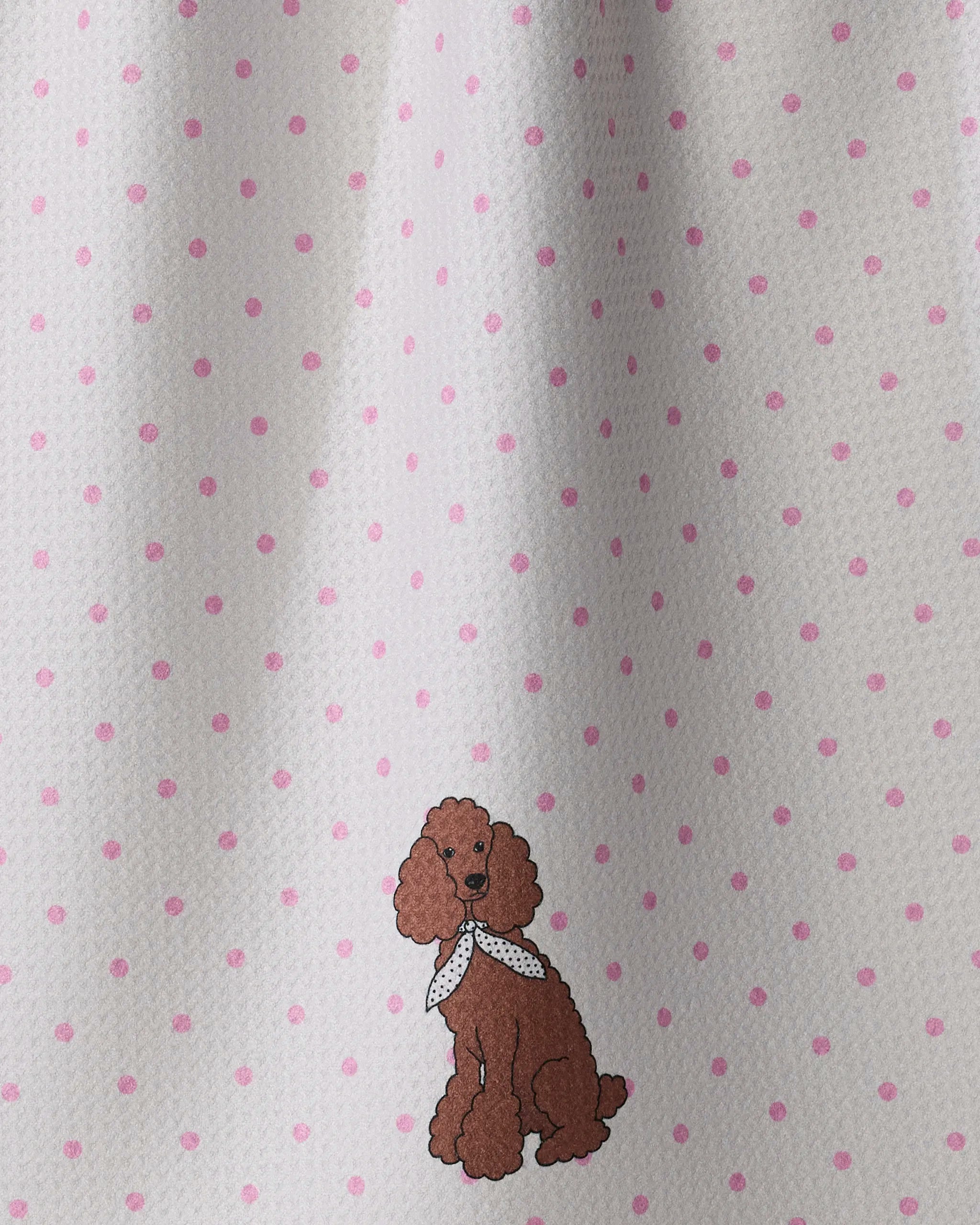 A brown cartoon poodle with a white scarf sits playfully atop Geometry’s ultra-absorbent Poodle Charm towel, set against a white background with pink polka dots.