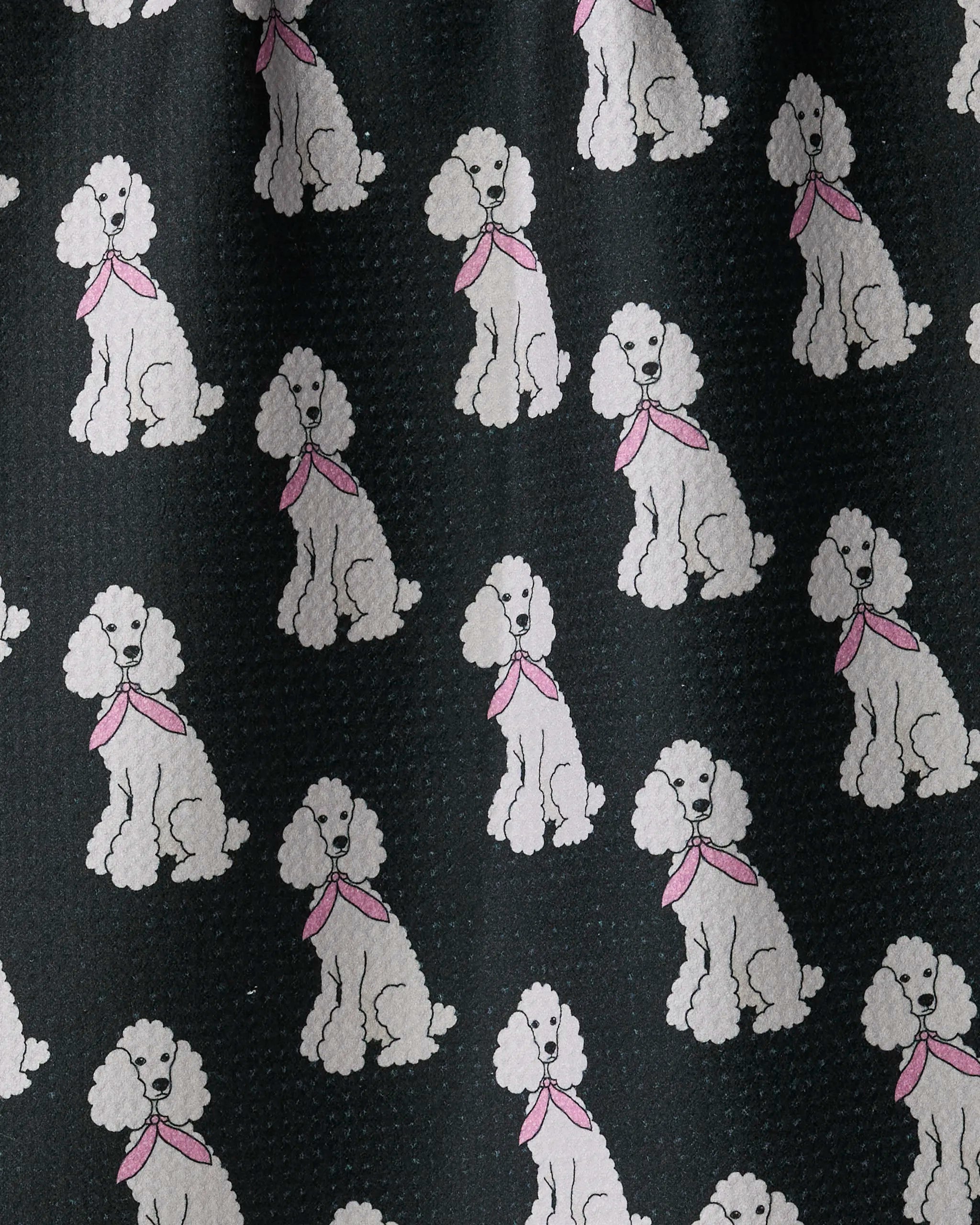 Introducing “Poodle Parade” by Geometry—a charming tea towel featuring a playful pattern of evenly spaced white poodles with pink scarves, all sitting and facing forward against a dark background. This absorbent and stylish towel is sure to brighten up any kitchen.