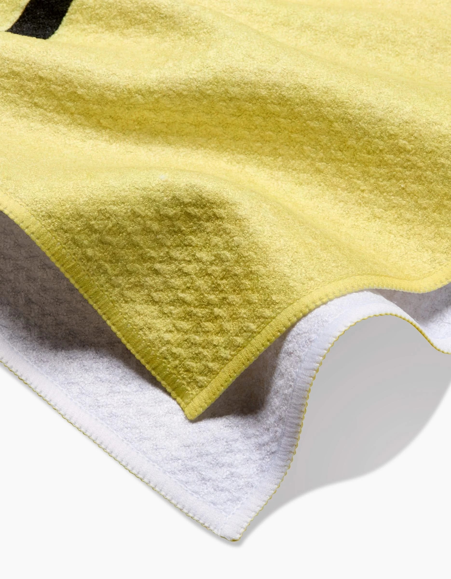 A close-up of the Poppies on Yellow tea towel by Rachel Austin, featuring a textured yellow surface made from recycled materials, white underside, and detailed edge stitching.